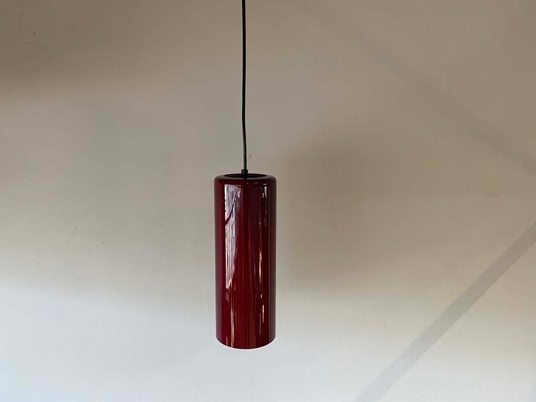 Schöne dänische Hängelampe aus den 190er Jahren. Die Lampe ist aus weinrotem Glas gefertigt und von innen mit Orange beschichtet. Wenn sie angezündet wird, ändert sich ihr Farbton in ein sattes Rot. Eine schöne Lampe für einen schmalen Raum mit