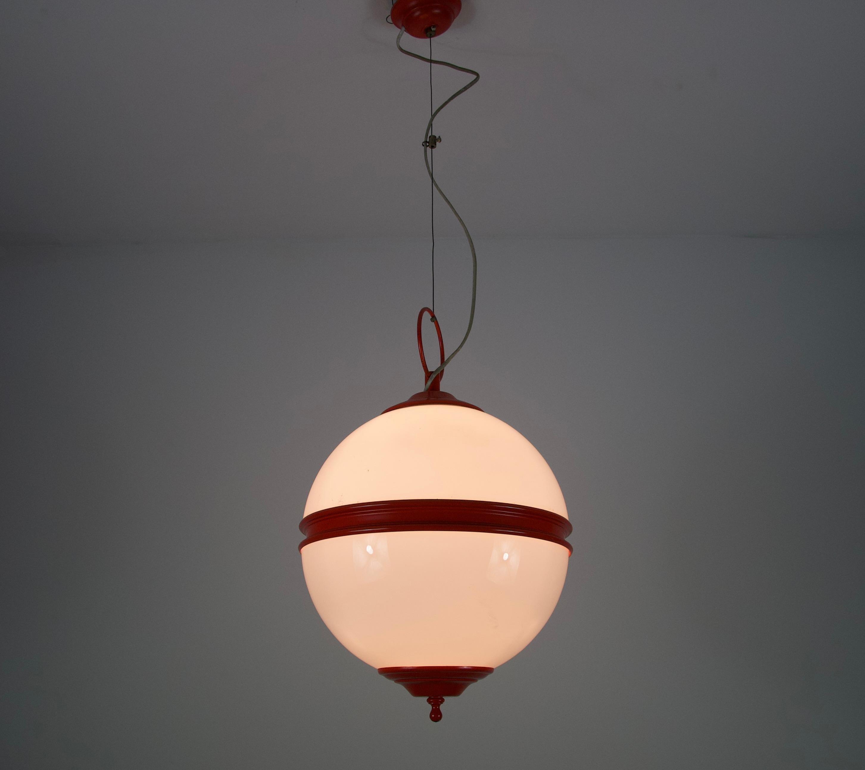 Questa sorprendente lampada da soffitto della metà del secolo scorso, risalente agli anni '60, cattura perfettamente lo spirito giocoso ed elegante dell'epoca. La lampada presenta un'audace struttura in metallo rosso abbinata a un globo in vetro