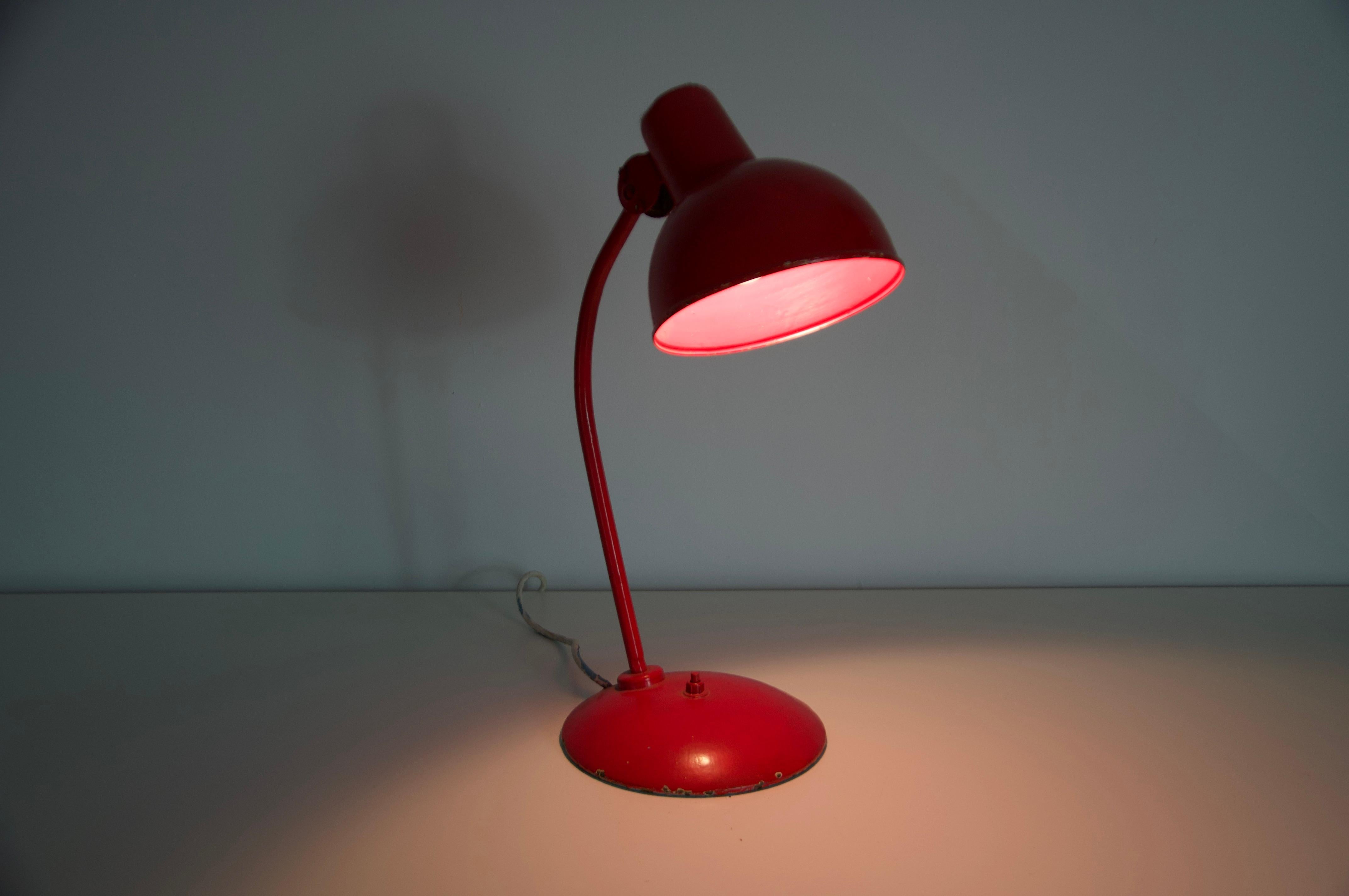 Esta llamativa lámpara de escritorio roja es una pieza original de los años 60, fabricada en Alemania por el renombrado fabricante Kaiser. Característica del diseño moderno de mediados de siglo, la lámpara presenta una silueta limpia y funcional con
