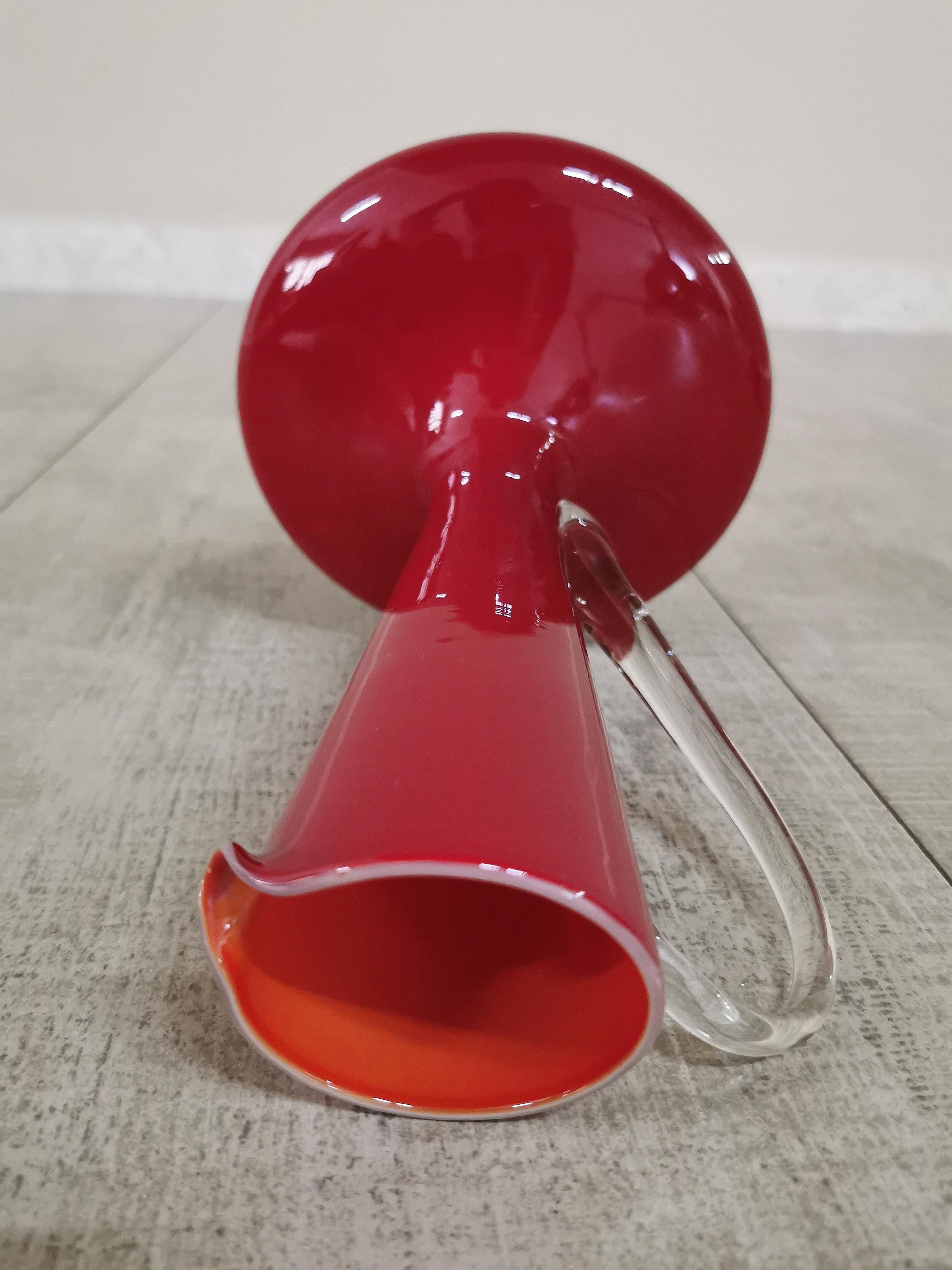 Set of 2 refined and elegant vases in red Murano glass, rounded below with a narrow mouth and transparent handle. Italian production from the 1960s.