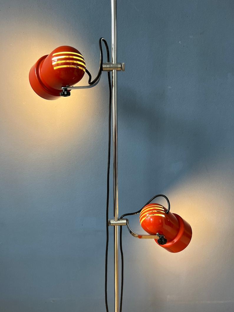 Mid century space age floor lamp in red colour. The metal shades can be turned in any way desirable and moved up and down the base. The lights can switched on separately or simultaneously. The lamp requires two E27/26 lightbulbs and currently has a