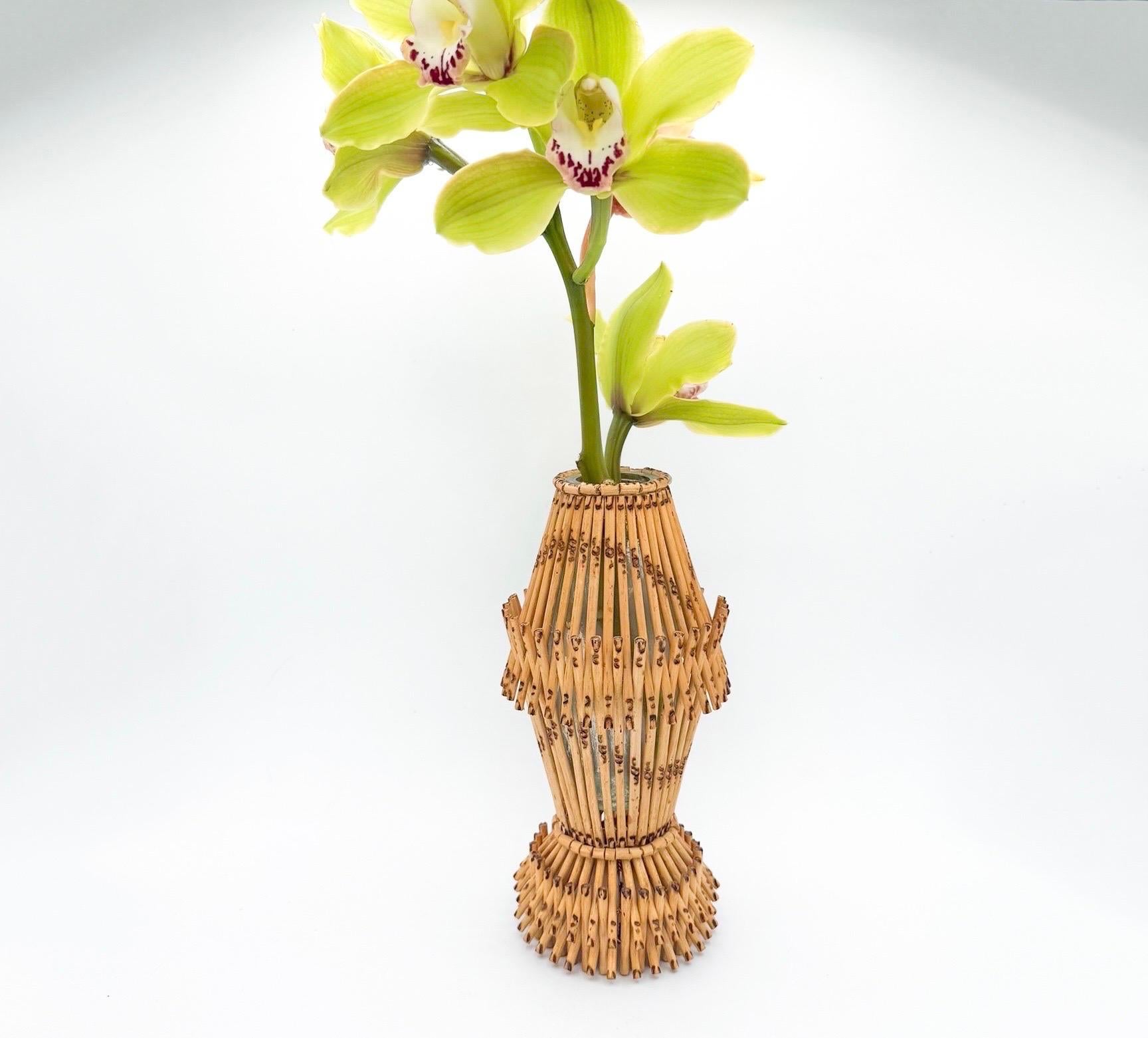 Este singular jarrón de mediados de siglo de 1970 es un bello ejemplo de artesanía natural y diseño práctico. Envuelto en caña de bambú tejida a mano con intrincados detalles y tonos cálidos y terrosos, aporta una rica sensación de textura y belleza