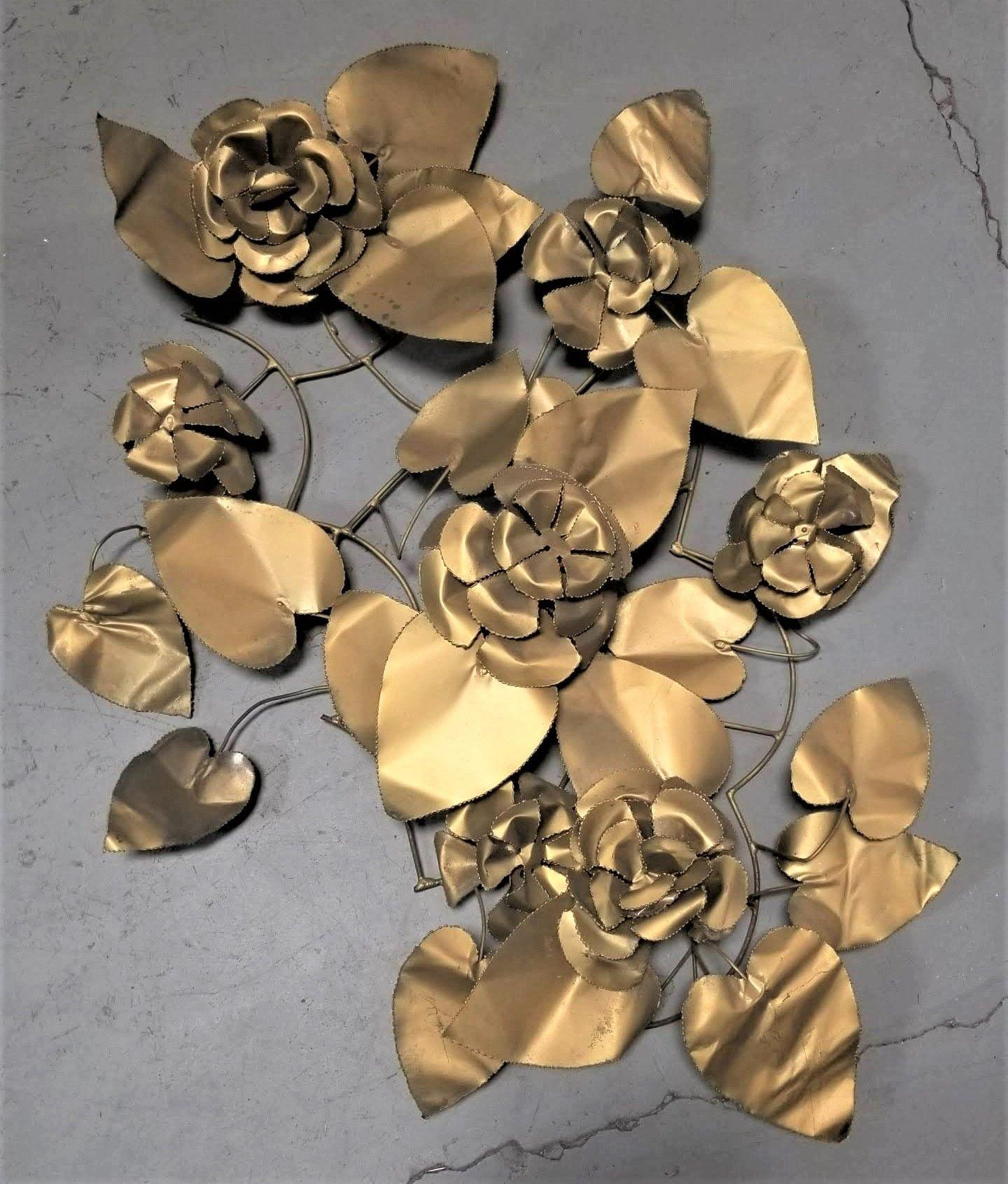 Post-War Regency style hand-folded metal floral wall sculpture.

Elevate your decor with this mesmerizing mid-century wall-hanging sculpture crafted from brass. Delicately formed flowers and leaves intertwine to create a stunning botanical