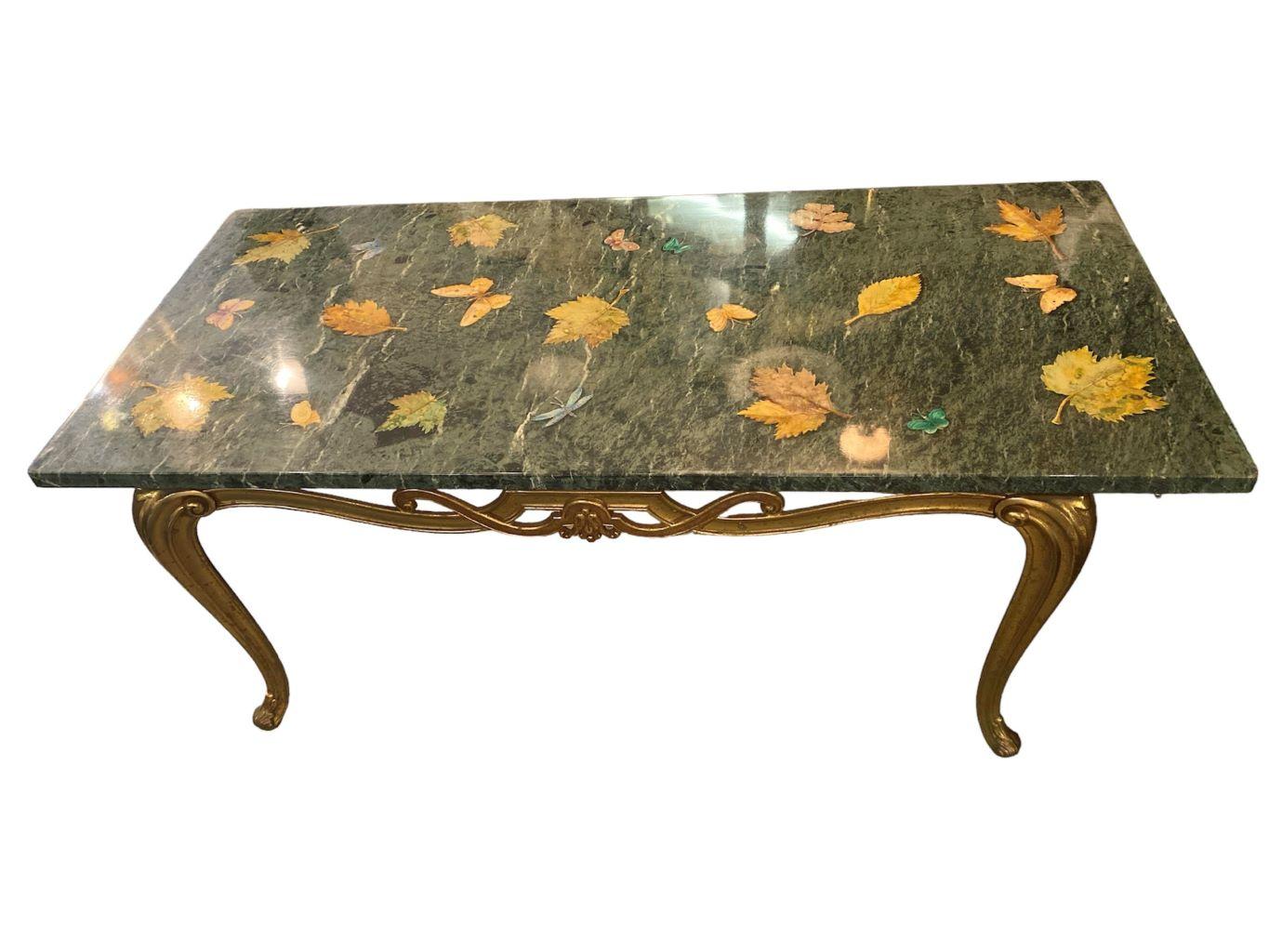 Cette table basse de style Regency du milieu du siècle est ornée d'incrustations de mouches à beurre et de détails de feuilles. Le marbre est d'un vert forêt et émeraude parcouru de veines blanches et noires. La table basse repose sur un cadre en