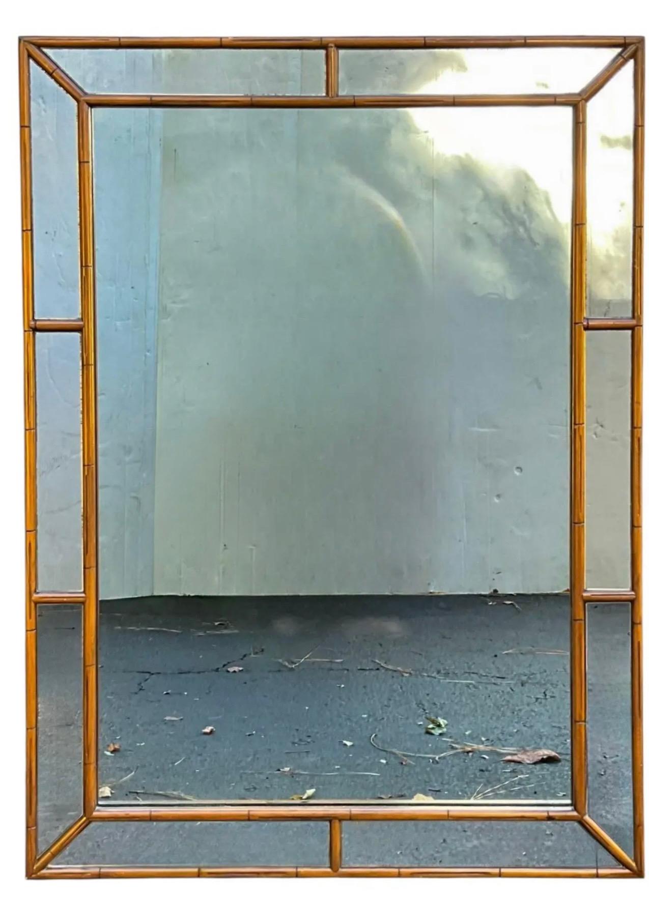 Si tratta di uno specchio da parete di metà secolo con una cornice in finto bambù intagliato. Ha uno stile reggenza e molto probabilmente risale agli anni '60. È in ottime condizioni ma la carta sul retro è strappata.
