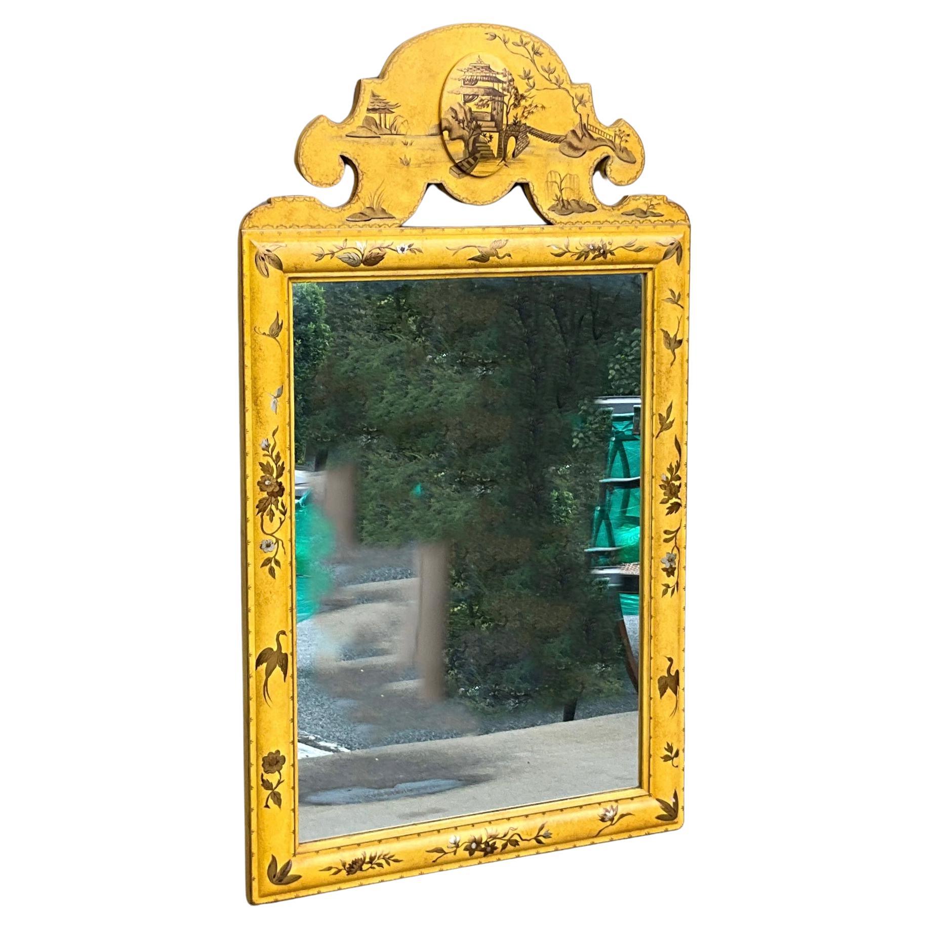 This is a mid-century hand painted regency style chinoiserie mirror. The carved wood cartouche is a mustard gold. The mirror is unmarked.