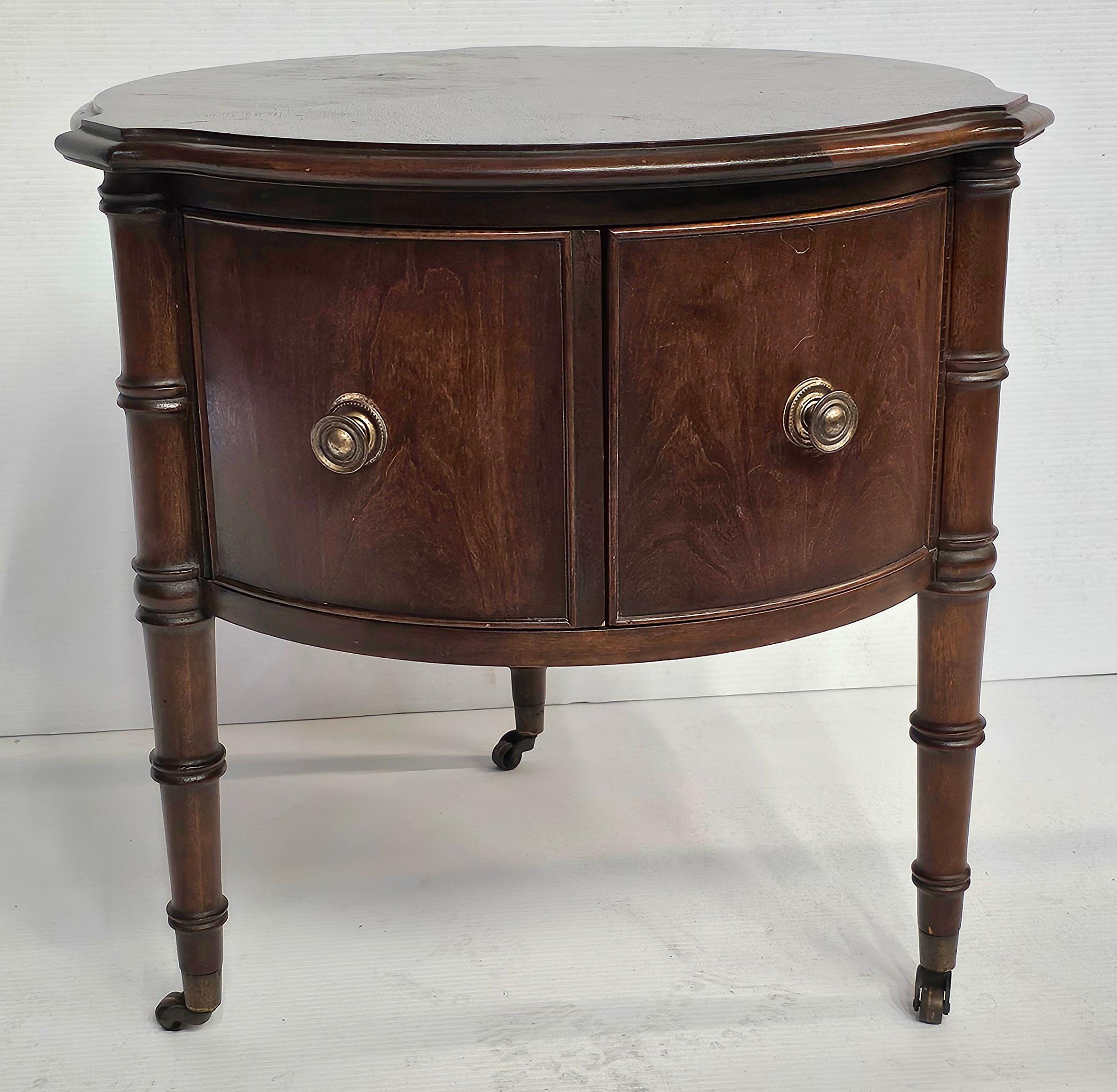 A Mid 20th Century Regency Style Walnut Rolling Trifid two-door  Storage Drum Side  Table with bookmatched top.
Measures 21.5