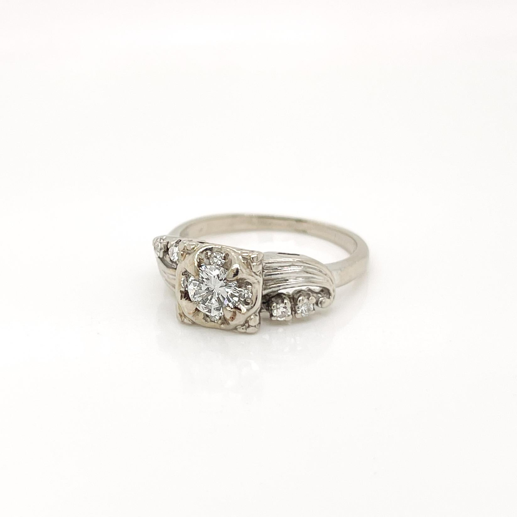 Anillo de compromiso de oro y diamantes de mediados de siglo. 

En oro blanco de 14 quilates con un diseño calado retro. 

Engastado con un diamante blanco talla brillante redondo de aprox. 0,38 quilates de diamante blanco engastado en el centro de
