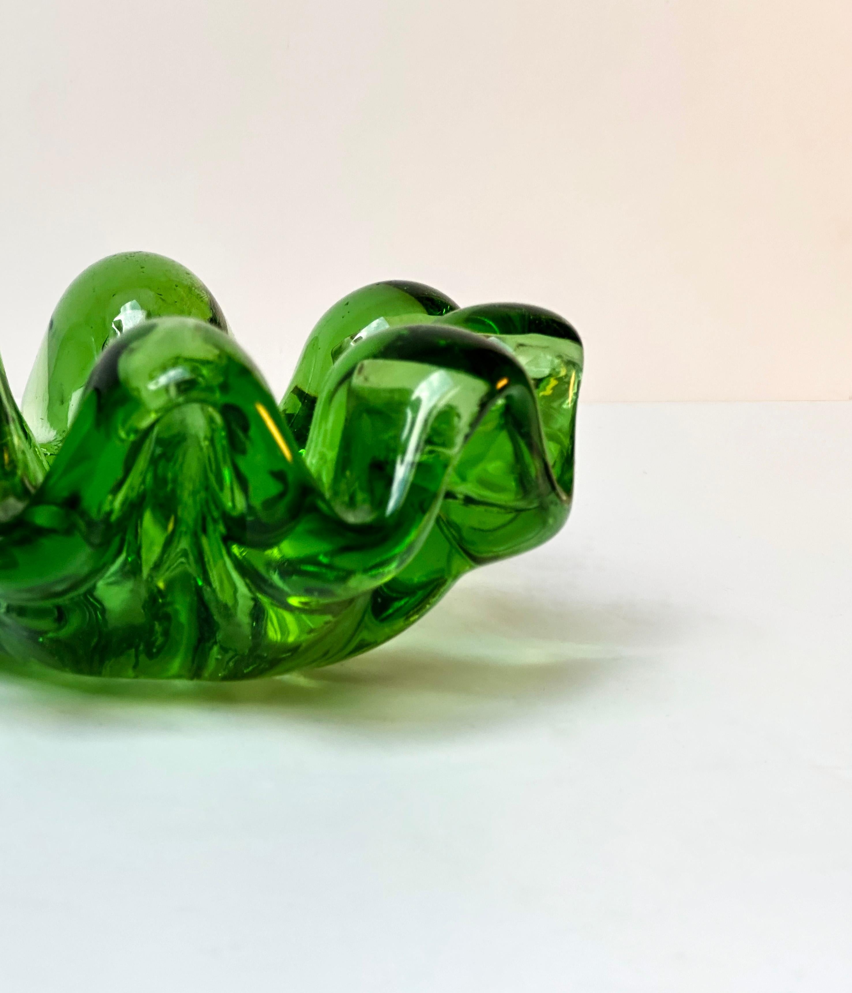 This Mid Century glass dish exudes a retro charm, crafted from luminous bright green glass. Its bold and vivid design draws inspiration from the iconic 'a grosse costolature' dish by Ercole Barovier. Featuring swags of bright green glass, the dish