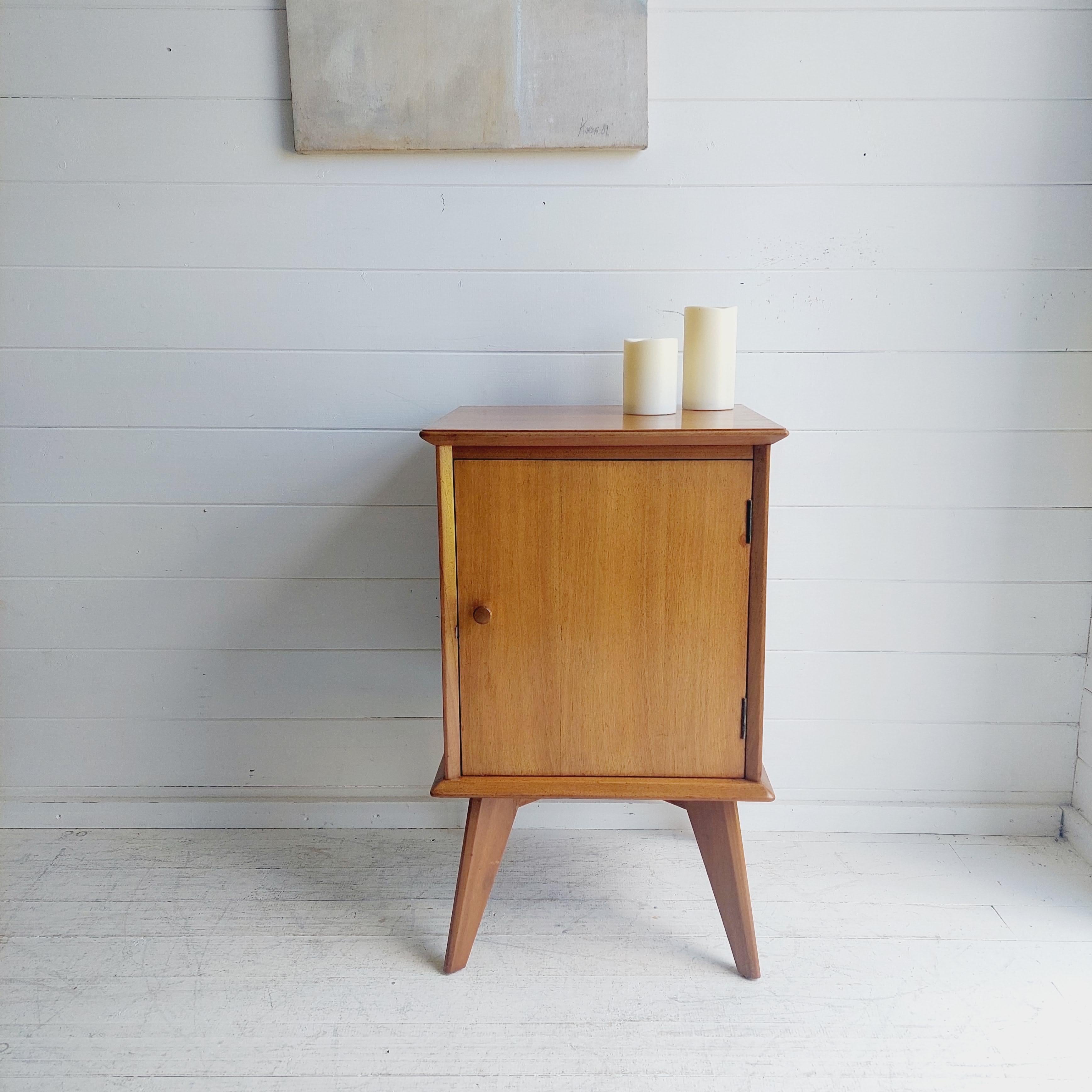 A stylish and extremely well made bedside cabinet in Walnut.
This was made probably by Alfred Cox, it dates from the 1950-60's. 

Featuring:
Lovely light coloured satin walnut 
Tall splayed hardwood legs 
Overhanging top surface and bottom base