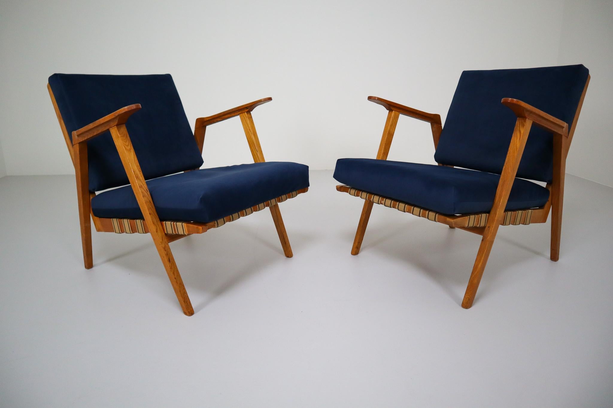 Unusually pair of original vintage midcentury armchairs / lounge chairs manufactured and designed in Czech republic 1960s. Made of ashwood and professionally reupholstered in blue velvet. These armchairs would make an eye-catching addition to any