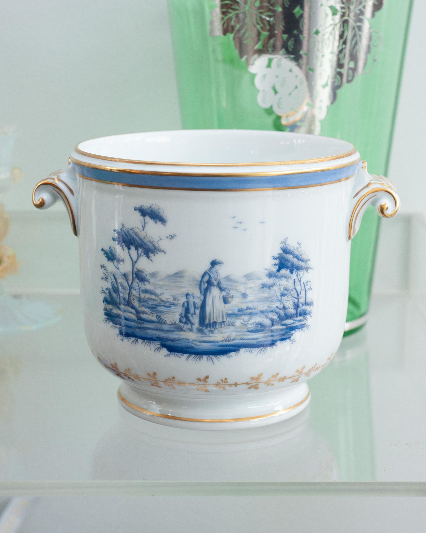 A beautiful mid century Richard Ginori Pittoria cachepot / planter. Elegant and classic, this cachepot has gilded features, scroll handles, and showcases two countryside scenes on each side in blue on a background of white porcelain. 