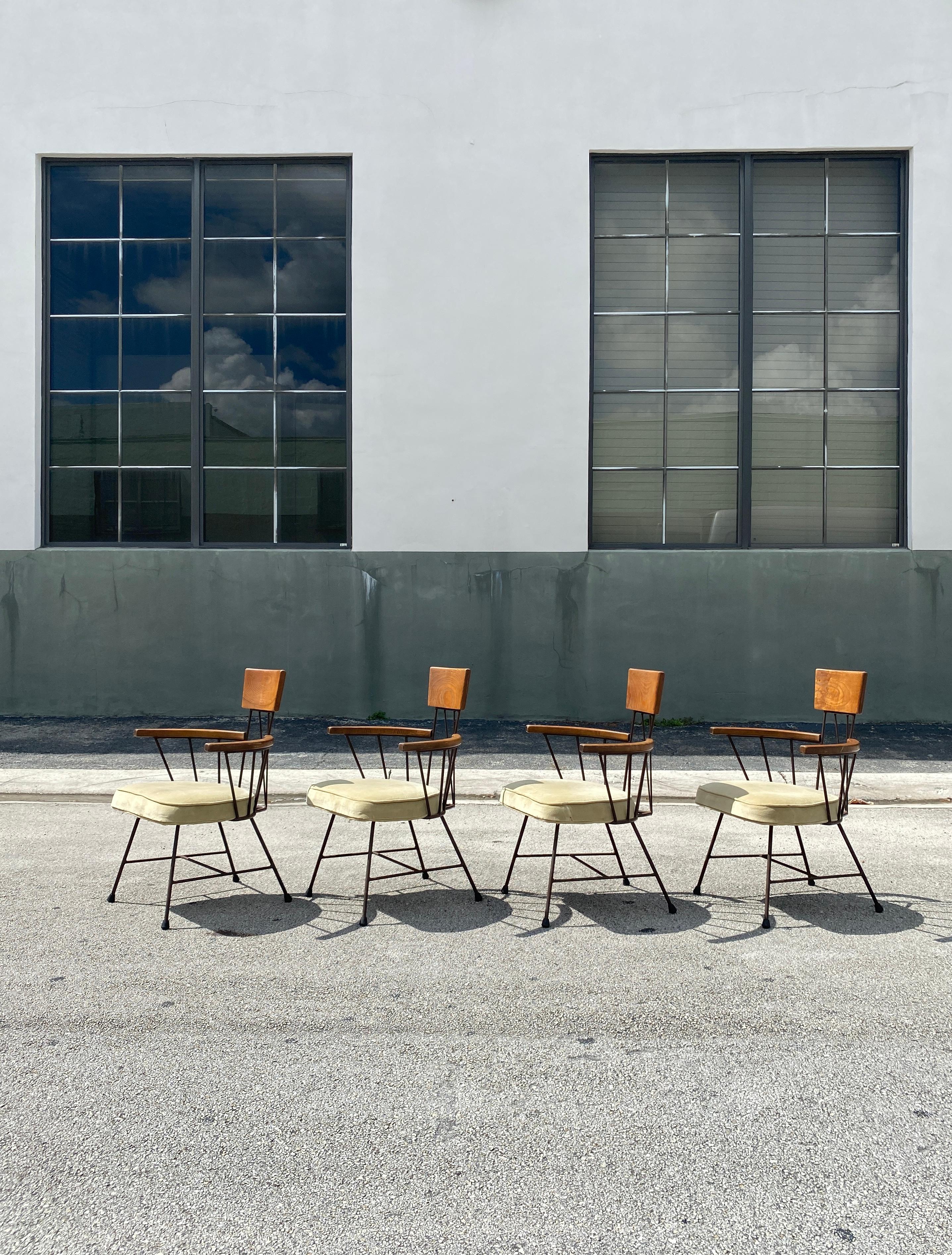 Unique vintage set of four dining chairs designed by Richard McCarthy manufactured by Selrite made of black painted iron against smooth wood featuring an industrial feel of the era. The armchairs feature curved wood arms and back headrest and