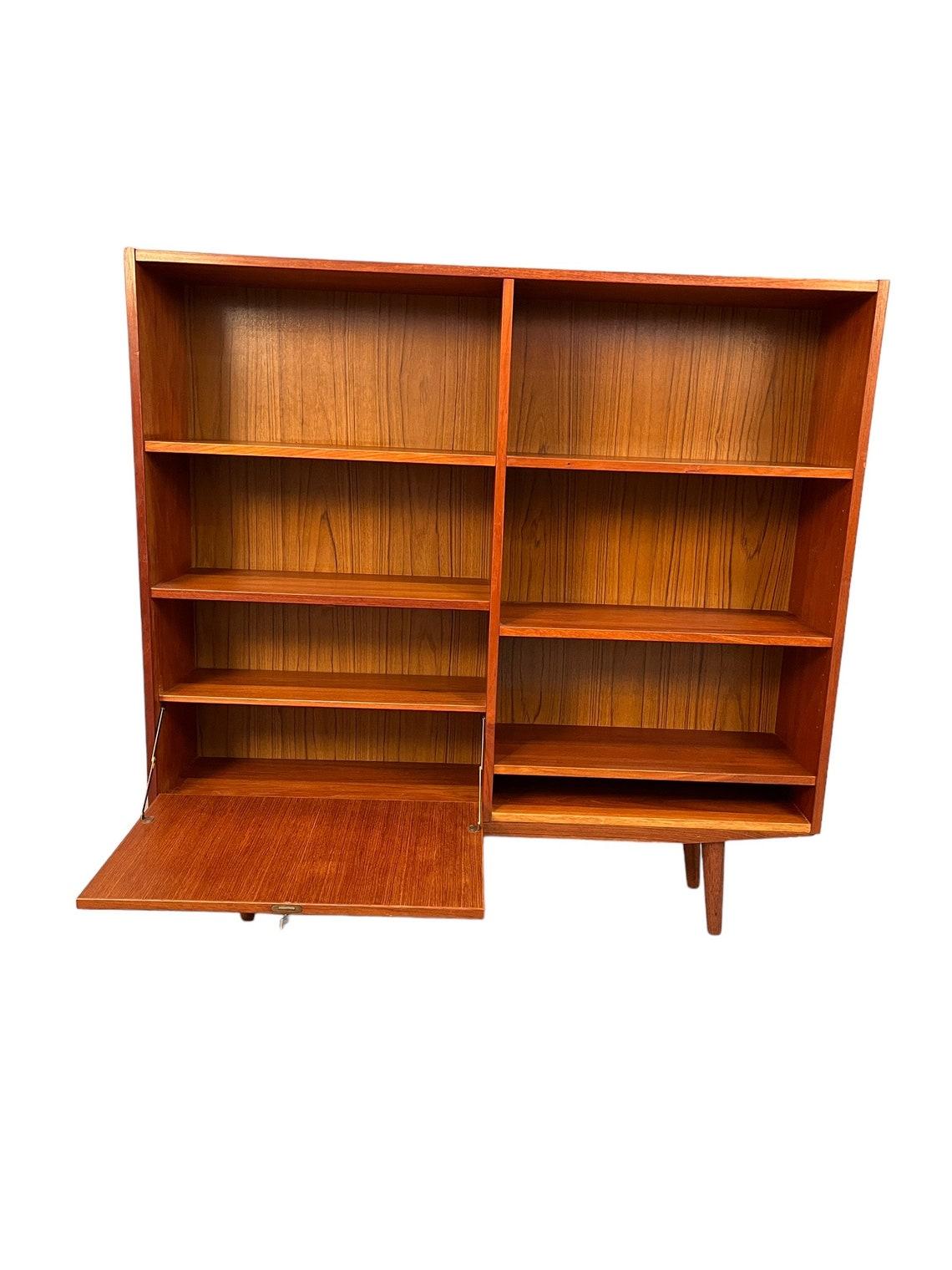 Mid-Century Teak bookcase on sharpened teak legs. 
This danish piece stands with plenty of storage and low cabinet.

Dimensions:
L:47 D:16 H:45 inches 

Condition:
very good for age and use