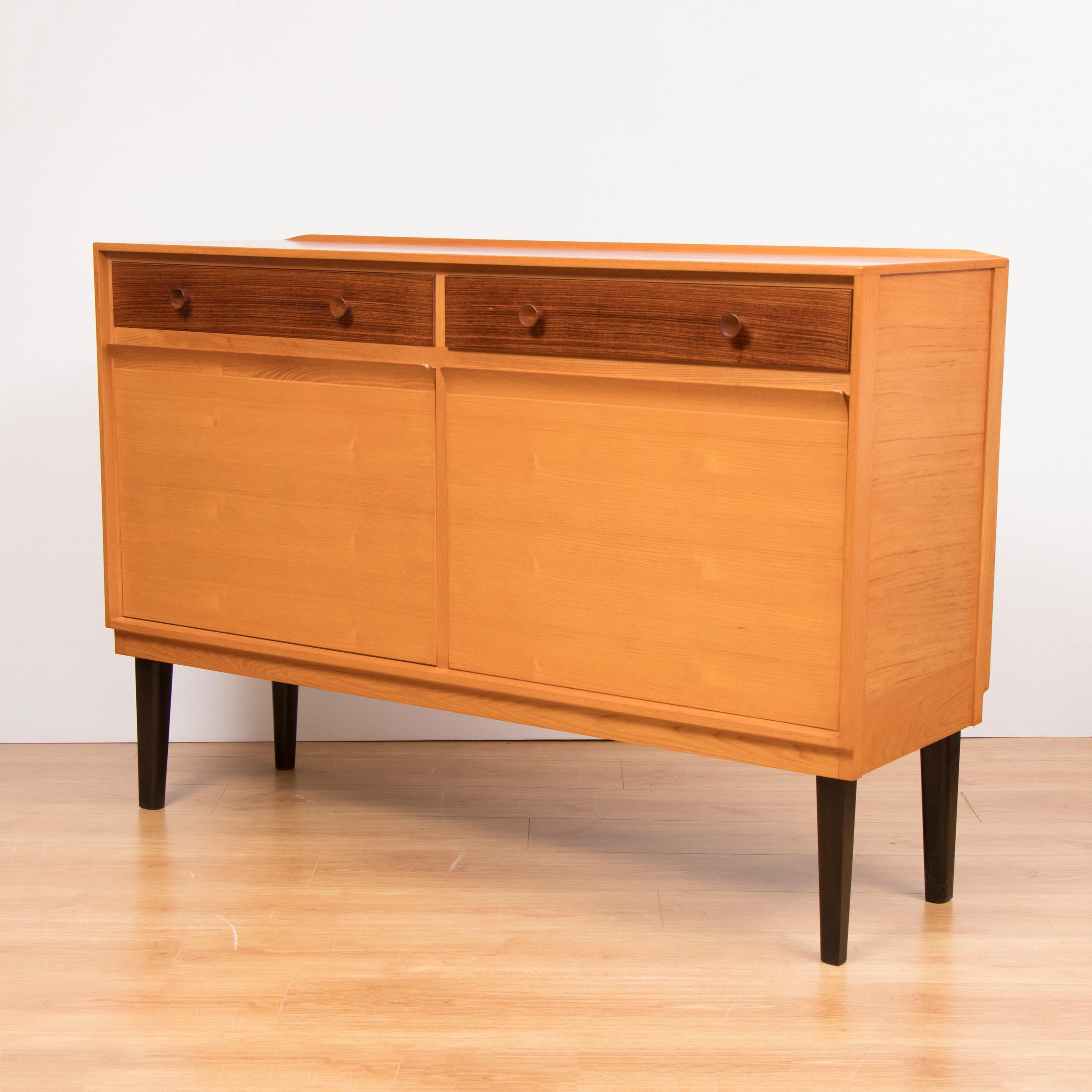 Midcentury sideboard credenza in a beautiful golden oakwood with contrasting Rosewood drawers.
Mid-Century Modern design. Robert Heritage sideboard credenza for Heals Tottenham Court Road London. A very early sideboard credenza designed by Robert