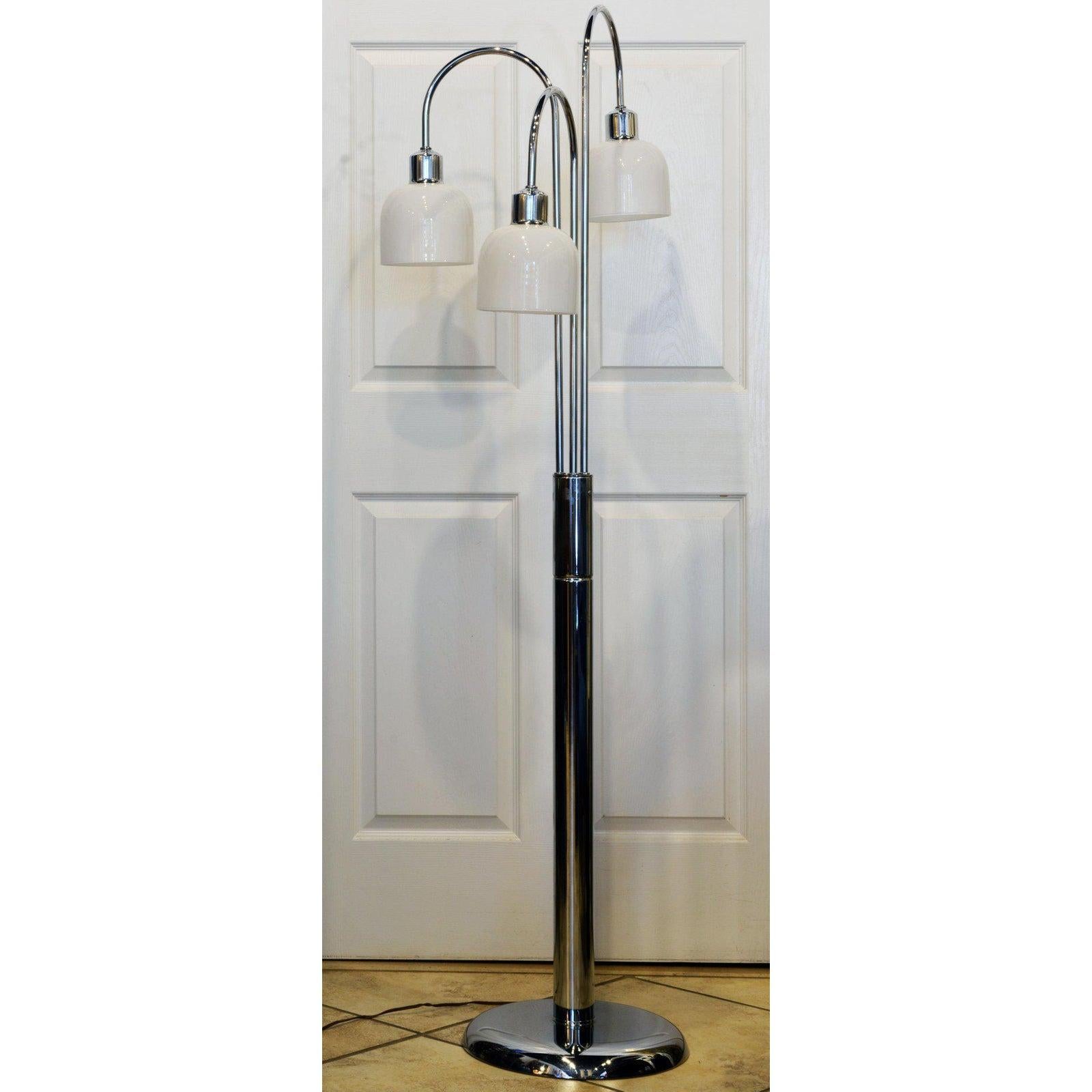 This midcentury chrome floor lamp in the Robert Sonneman style features three arched light arms with handblown milk glass shades set on a central stem with switch on a heavy domed base. The glass shades are easily detachable.