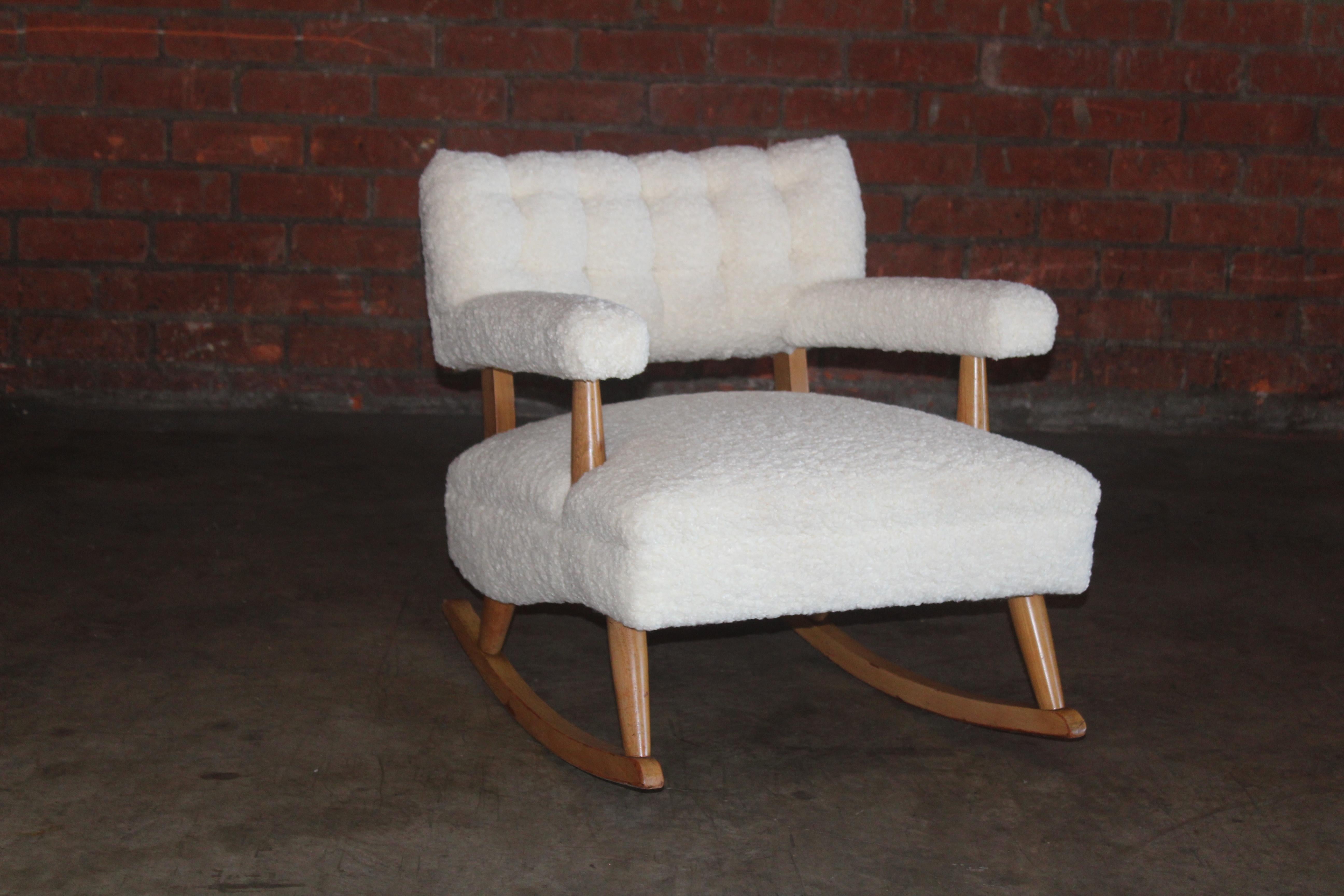 A vintage mid-century rocking chair attributed to Billy Haines. Features tufted upholstery with new curly wool Belgian boucle fabric. The solid maple frame is in good condition with minor signs of wear. Arm height is 24