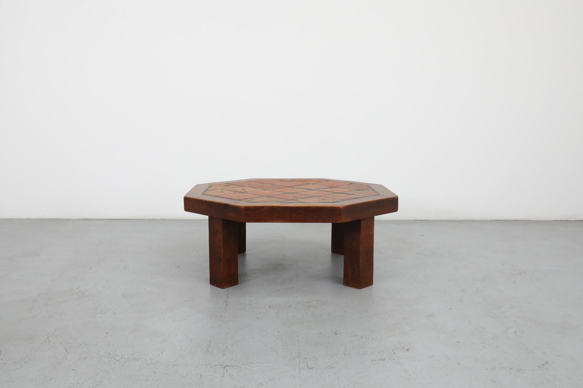 Heavy Mid-Century octagonal oak coffee table inspired by Roger Capron with inset ceramic tile in tones of burnt orange with charcoal grout. In original condition with wear and patina consistent with age and use.