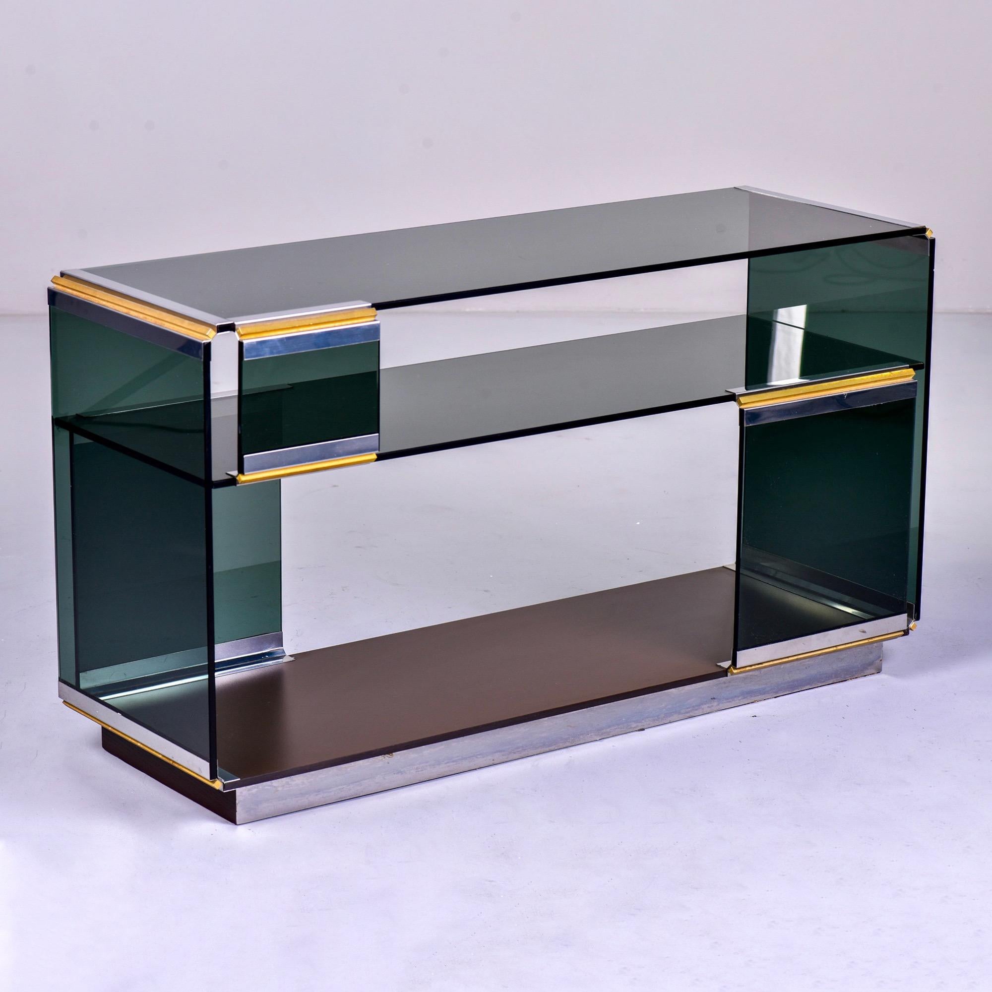 Console attributed to Romeo Rega of Italy, circa 1970s. Smoked glass panels set in polished nickel frame with brass accents.

Overall very good condition with some scattered nicks/wear to glass. Some rust/wear to metal at base. See detail photos.