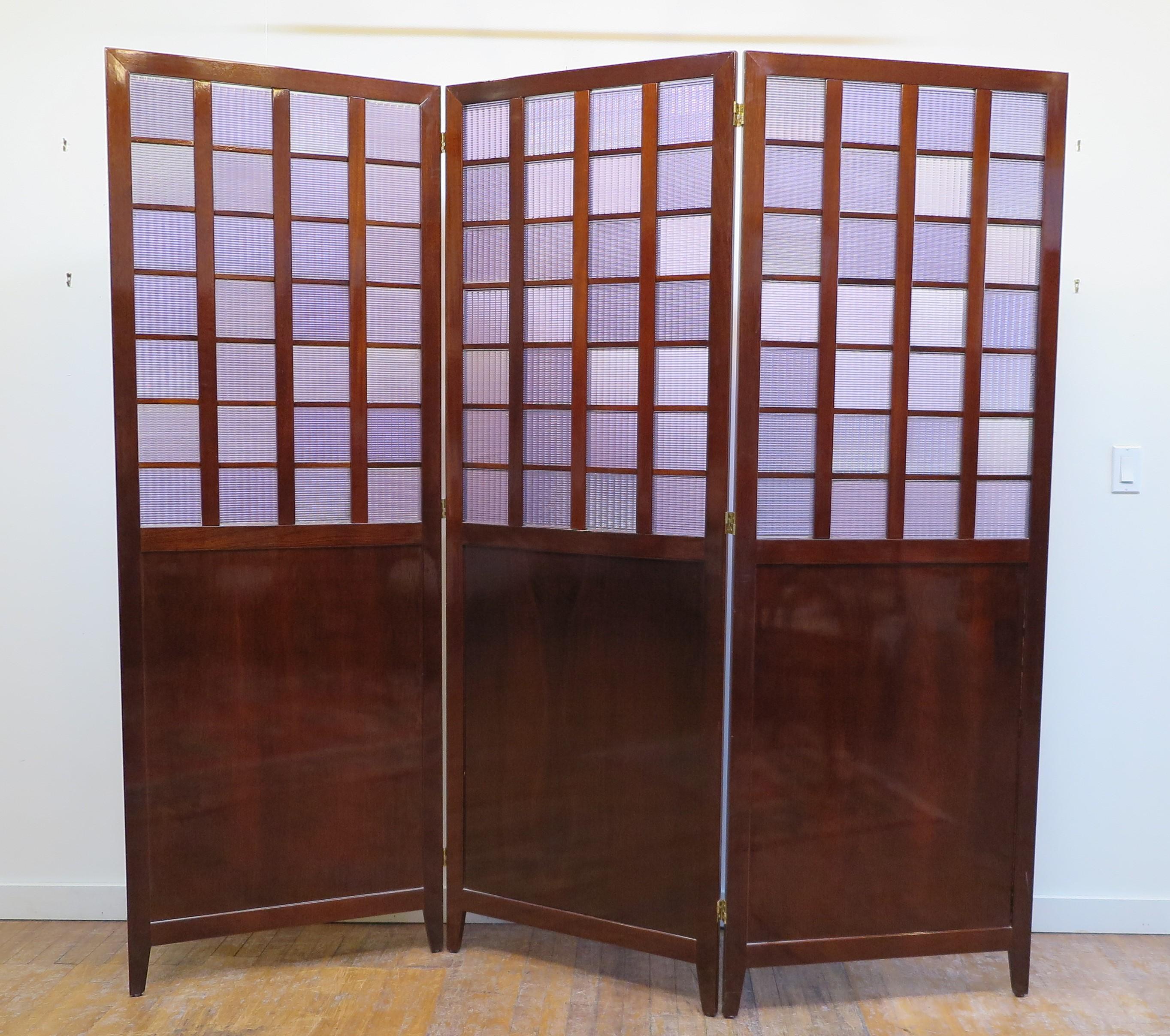Bendheim Glass panel room divider privacy folding screen. Mahogany panels with colored molded glass set in squares creating a geometric design. Bendheim press molded glass squares having a Lilac colored tint acescent three mahogany wooden panels on