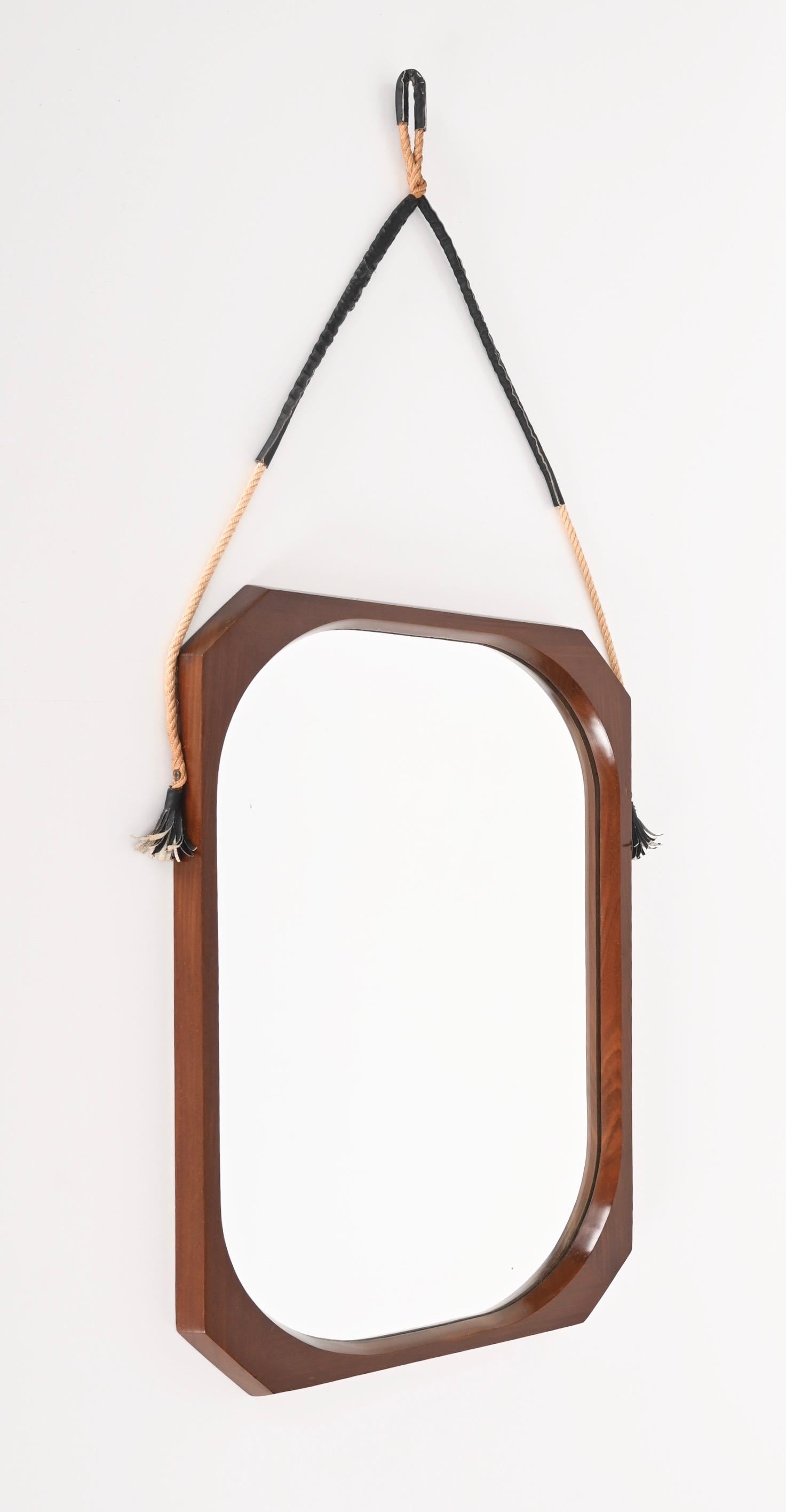 Amazing midcentury teak, rope and leather octagonal wall framed mirror. This wonderful piece was produced in Italy in the 60s by Domustil.

The mirror features a beautiful octagonal frame in teak wood with stunning wood grains, that seems to float