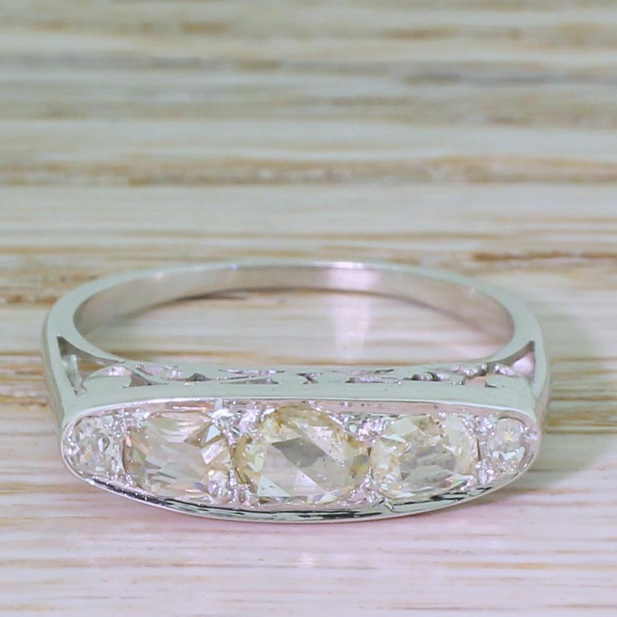 A super pretty and unique vintage five stone ring. At the centre is an oval shaped rose cut diamond set laterally between a pair of glacially cool cushion shaped old mine cuts (also set laterally) and two round old cuts at either end. The decorative