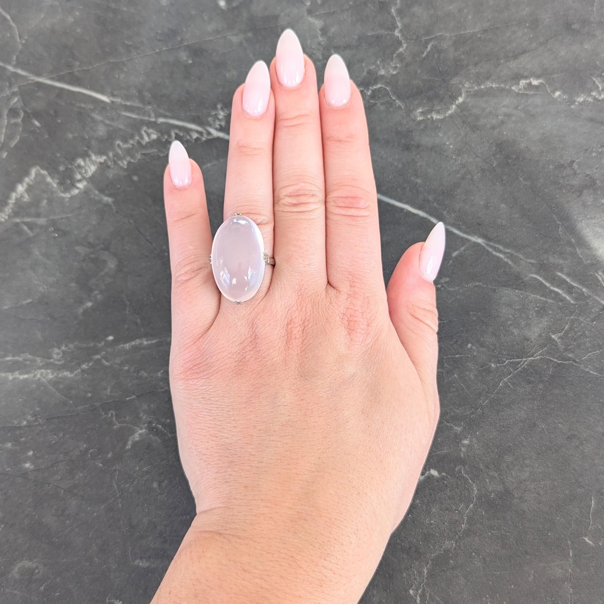 Centering an oval shaped rose quartz cabochon measuring 16.5 x 26.5 mm
Translucent very light peachy pink in color - set with split talon prongs
Accented by a pierced striated scallop pattern gallery
Flanked by pierced geometric motif