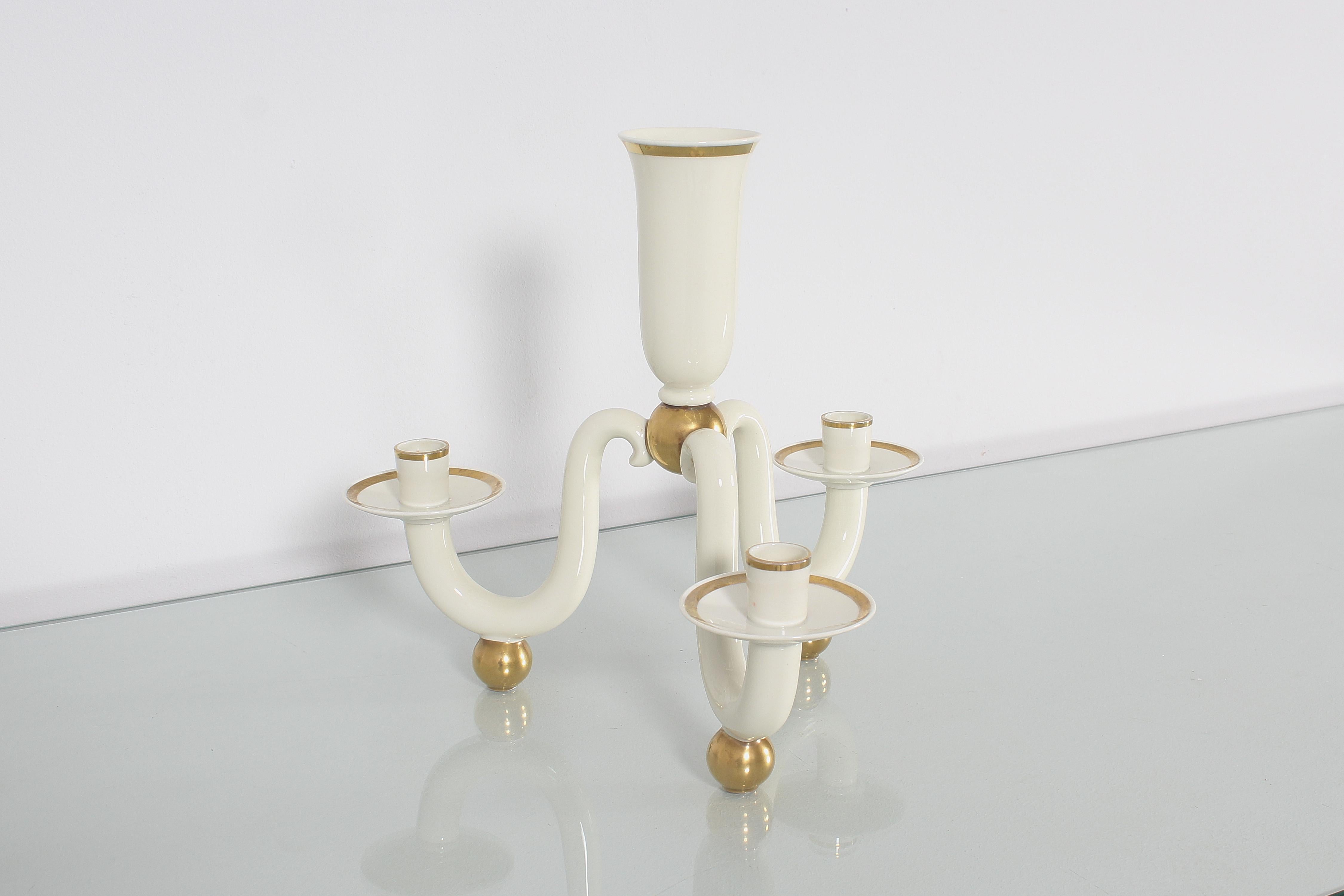 Refined classic style candelabra with three curved arms and a central body for a larger diameter candle, in very fine creamy white porcelain with golden profiles and support spheres, signed Rosenthal. Trademark printed under one of the three support