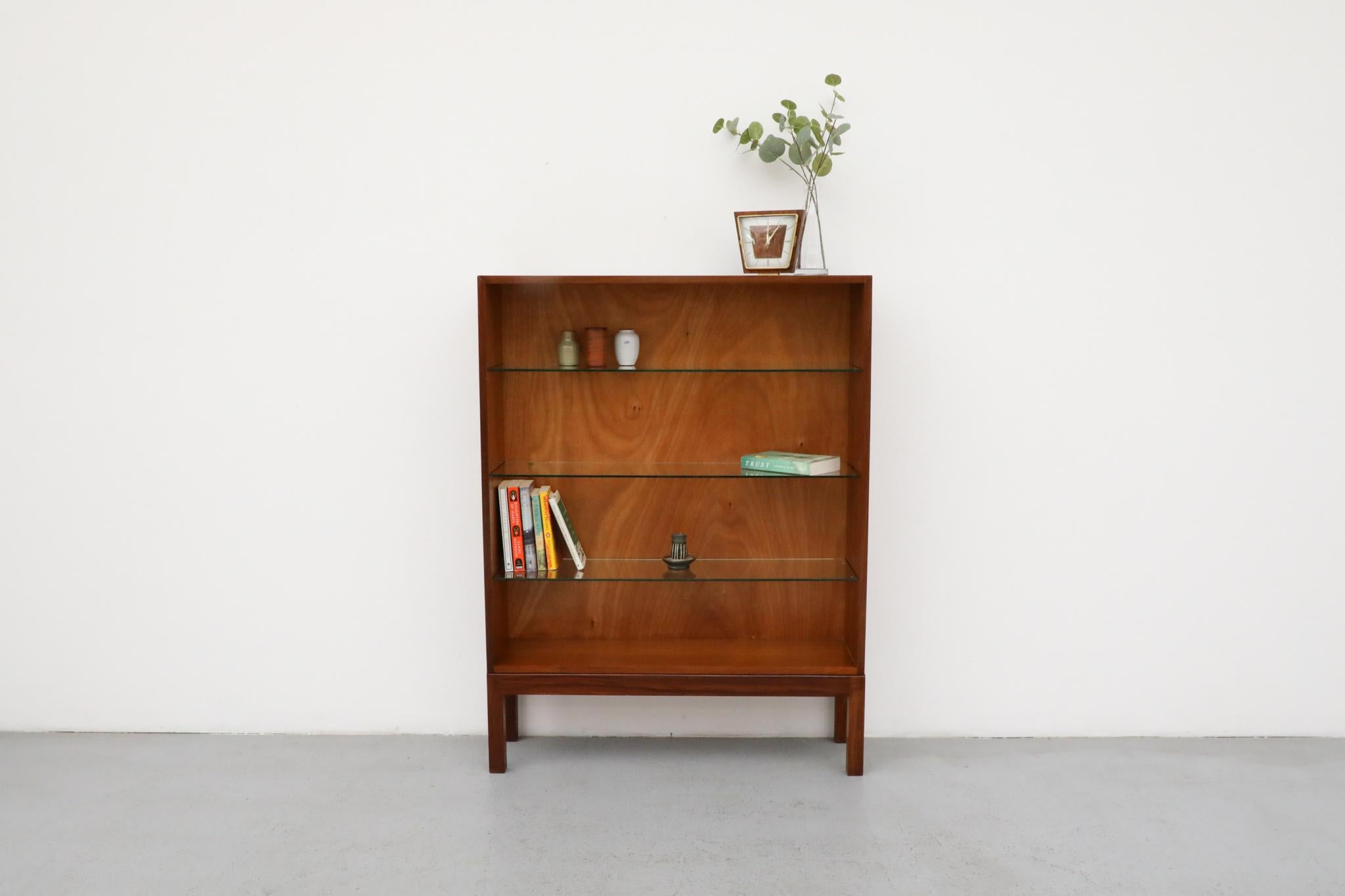 Libreria a giorno di metà secolo realizzata in legno di palissandro riccamente venato, probabilmente prodotta negli anni Sessanta. Questo mobile contenitore minimalista è caratterizzato da tre ripiani in vetro regolabili in altezza che poggiano su