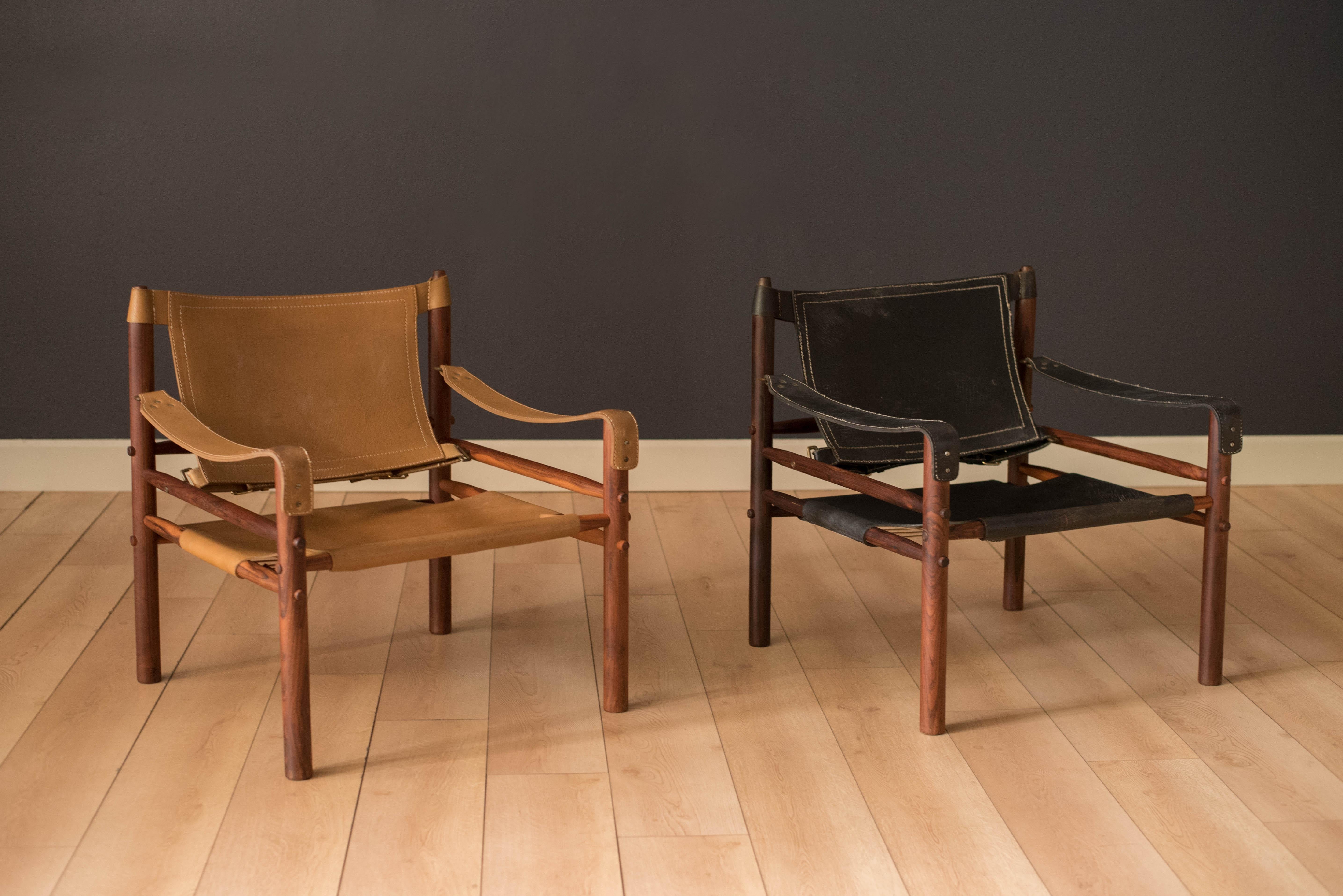 Vintage Sirocco Safari lounge chairs in rosewood designed by Arne Norell for Möbel AB, Sweden. Features the original handstitched slings in black and natural tan leather accented with brass hardware. Price is for each, please specify color.