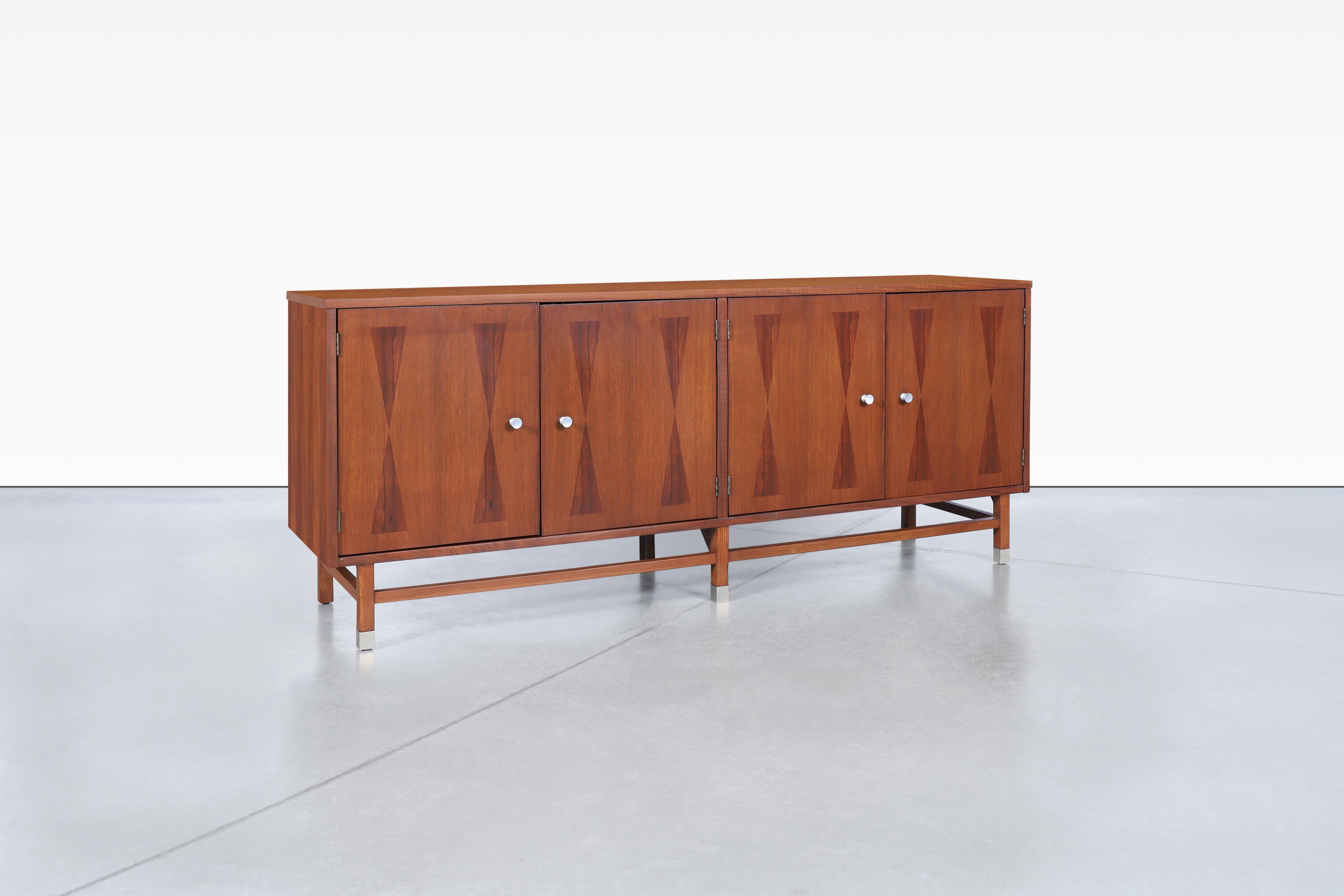 A stunning mid-century credenza that embodies the elegance and functionality of 1960s design, expertly crafted by Stanley in the United States. This piece showcases a refined combination of rosewood and walnut, creating a visual masterpiece that