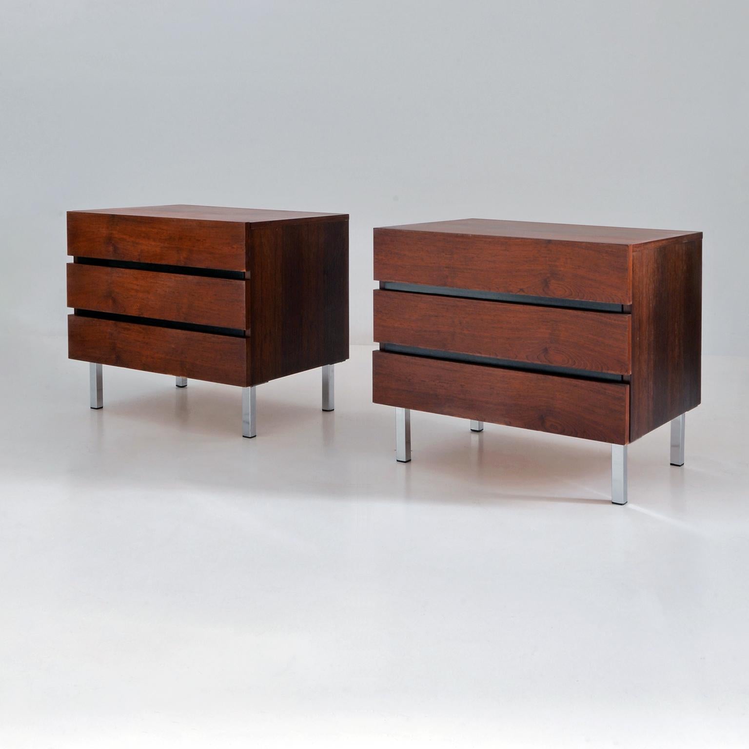 Mid-century nightstands in rosewood veneer, each with three drawers. The rectangular cabinets stand on four rectangular chromed metal feet. The general vintage condition is good.