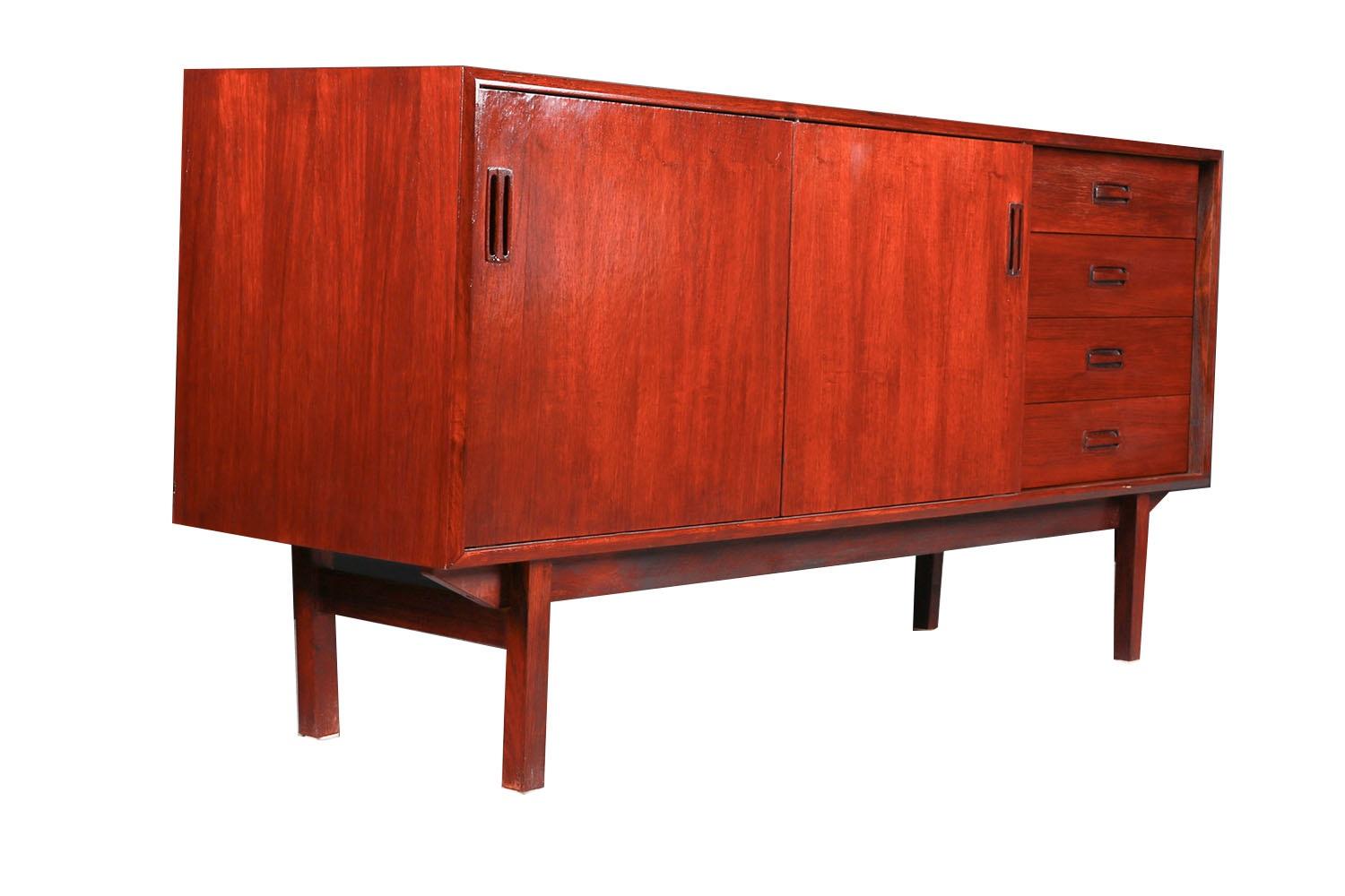 Exceptional Mid Century rosewood sliding door credenza or server, circa 1960’s. Beautifully rosewood grained, credenza. Features two sliding cabinet doors and four dovetailed drawers with carved pulls. Top two drawers are felt lined. The sliding