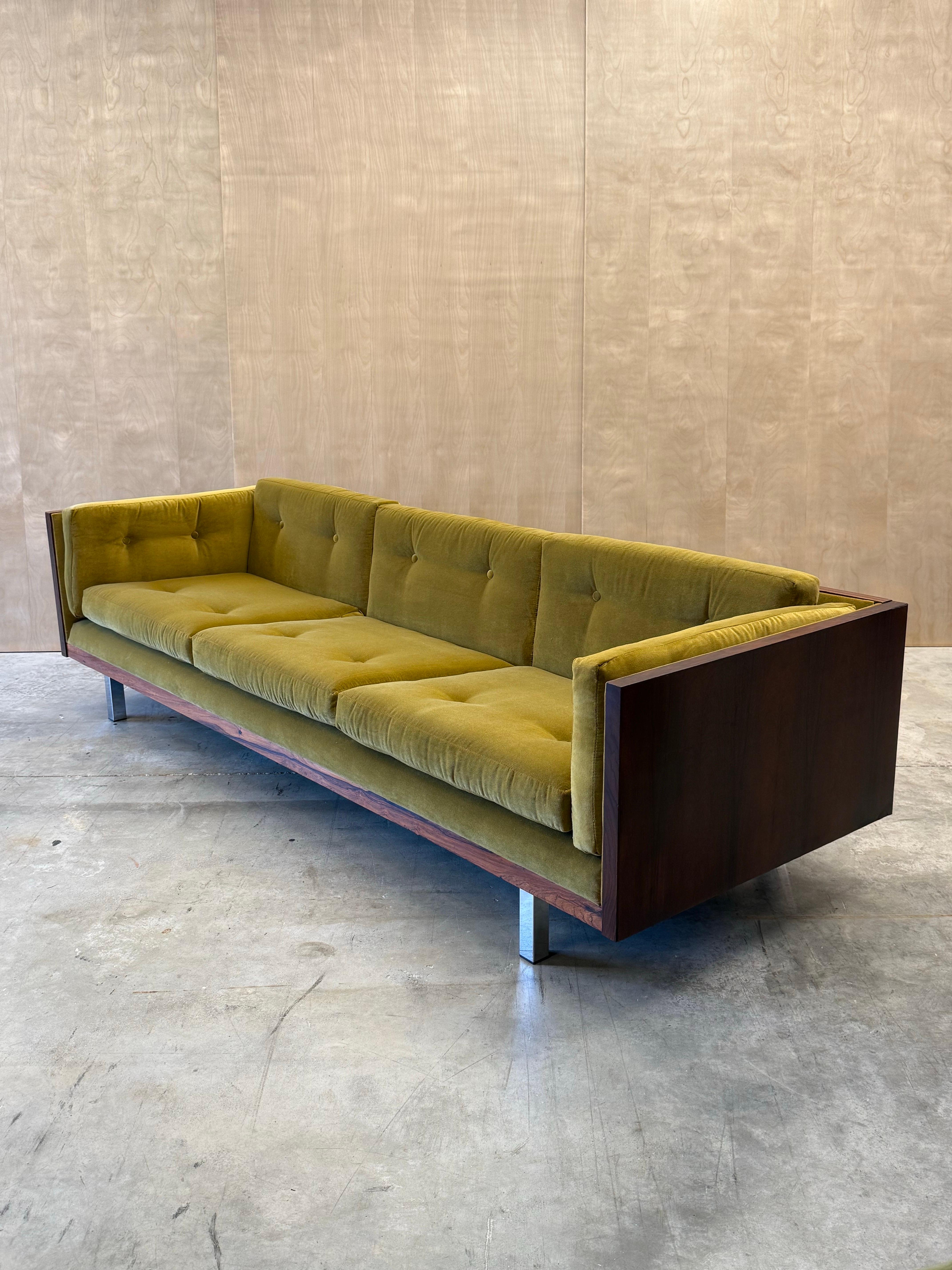 Canapé d'appoint du milieu du siècle conçu par Jydsk Møbelvaerk, fabriqué au Danemark vers les années 1960. Ce canapé est habillé de notre essence de bois préférée, le palissandre. Le dossier et les côtés sont enveloppés d'un riche grain de bois de