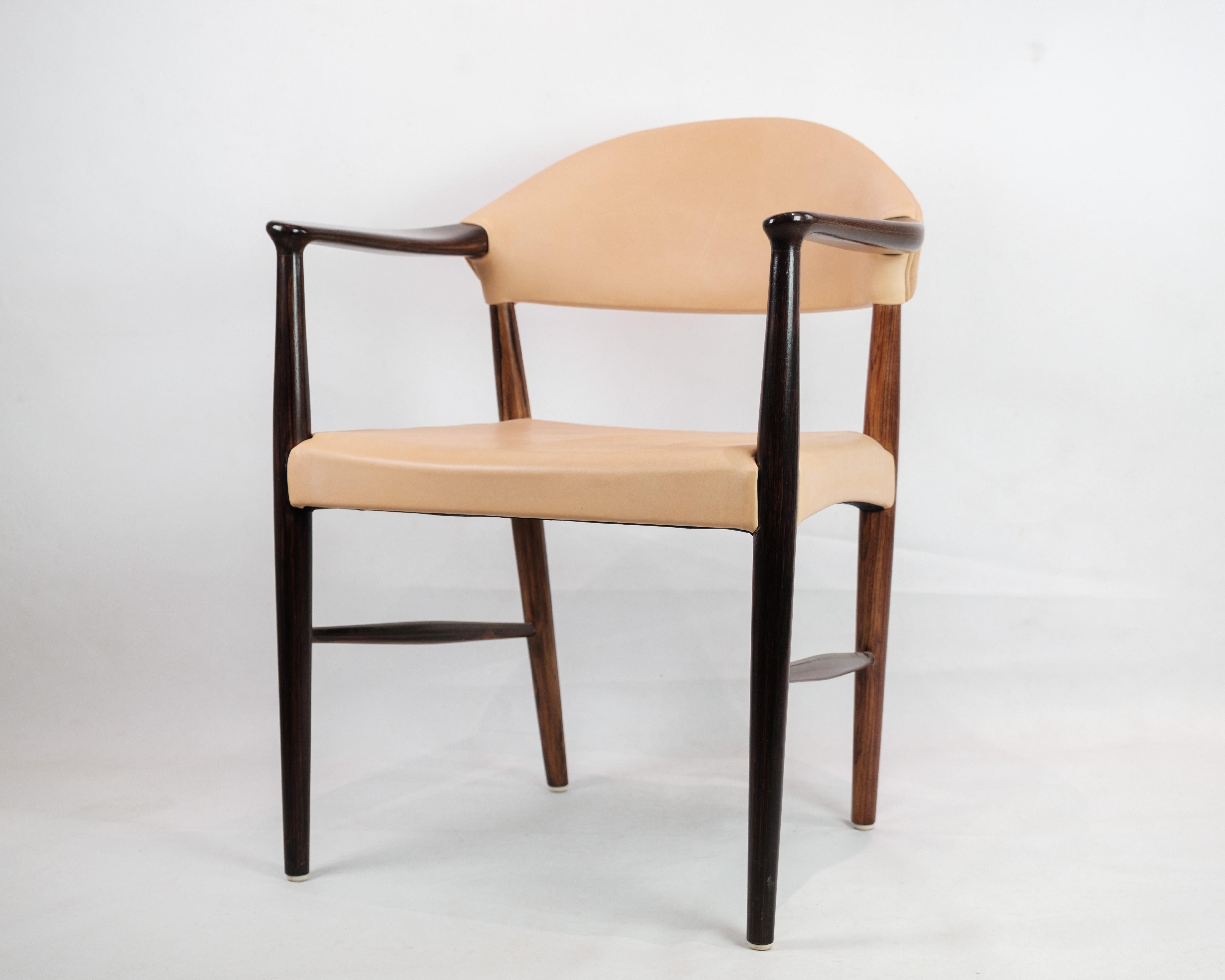 Dieser Schreibtischstuhl/Sessel aus luxuriösem Palisanderholz, ergänzt durch einen hellen Naturlederbezug, ist ein zeitloses Stück dänischen Designs aus den 1960er Jahren. Dieser Stuhl wurde von dem talentierten Designer Kurt Olsen entworfen und