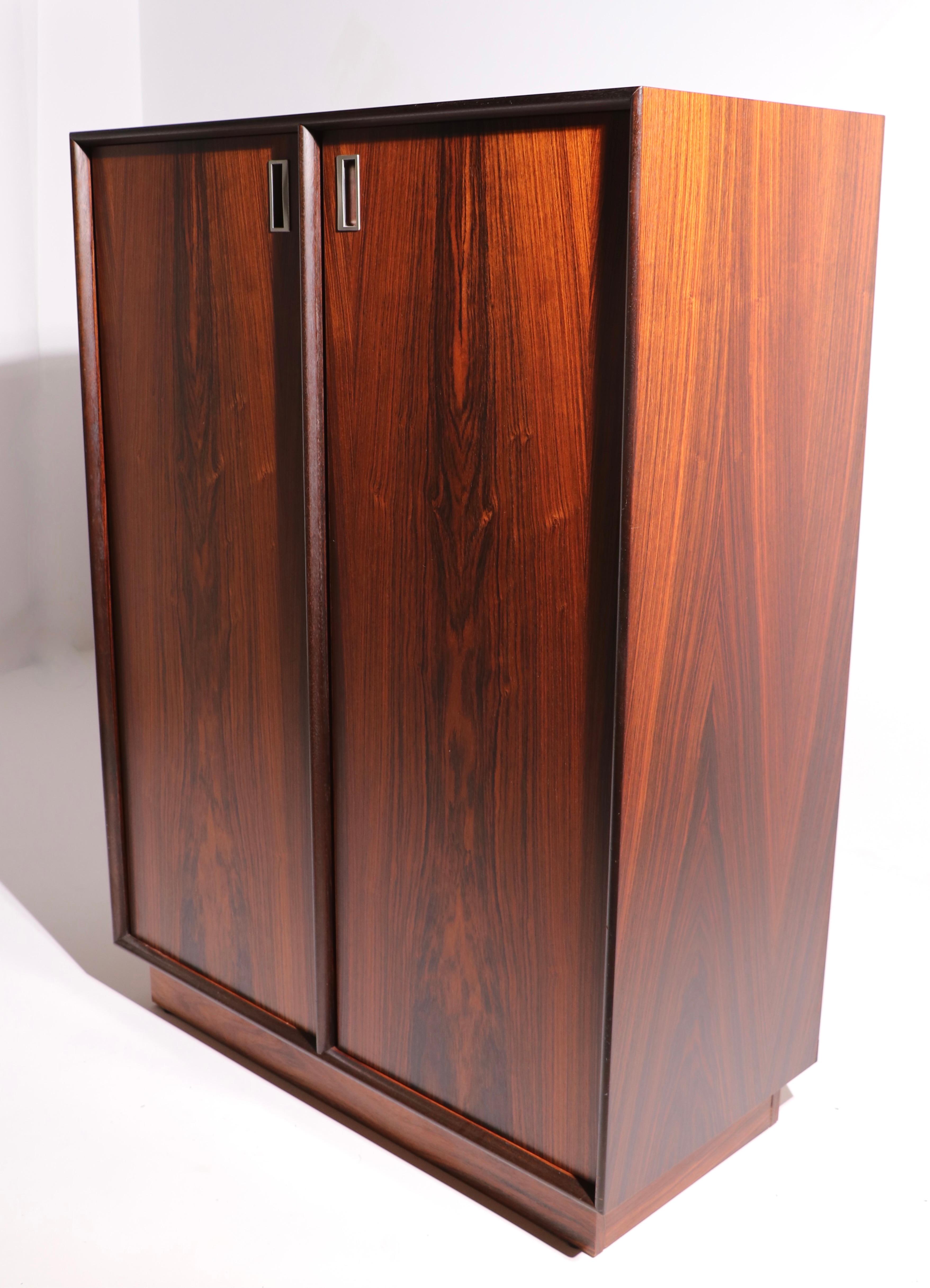 Stunning rosewood chiferobe, amoire having two doors, which open to shelved storage and interior drawers. The wardrobe is in excellent , original, clean and ready to use condition. Please view the companion dresser, and nightstands we have listed