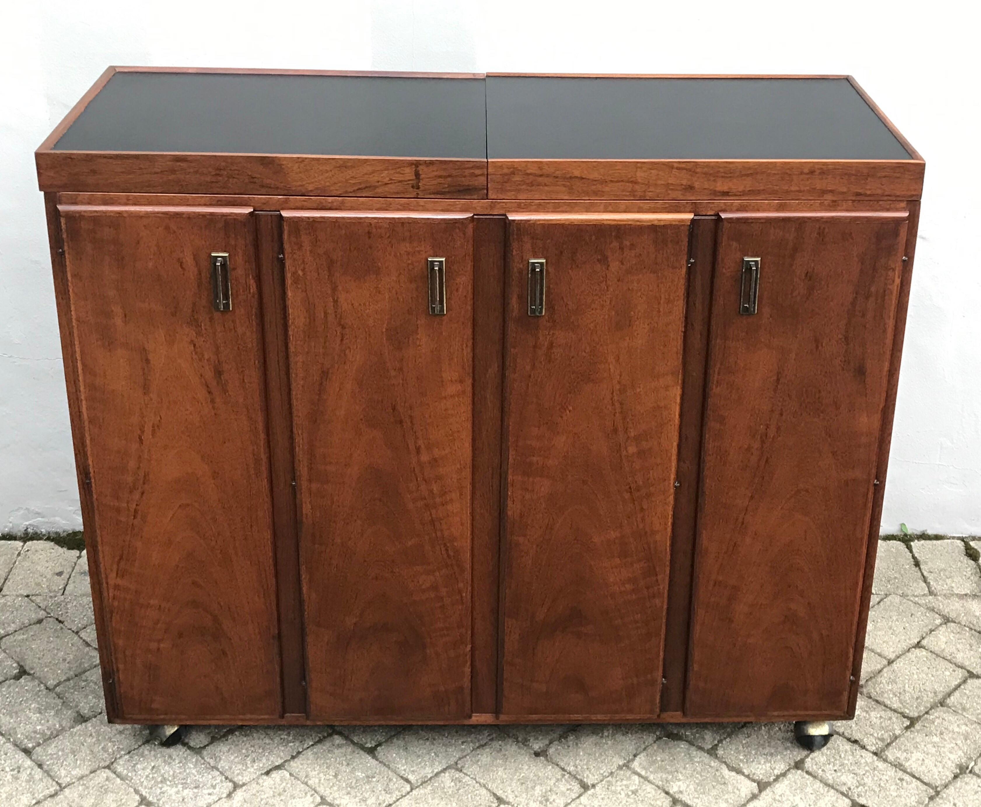 Beautiful midcentury rosewood cocktail bar designed by Jack Cartwright for Founders Furniture Co, 1960s. Sliding expandable top, adjustable shelving, on rolling castors and finished back for free floating room placement.