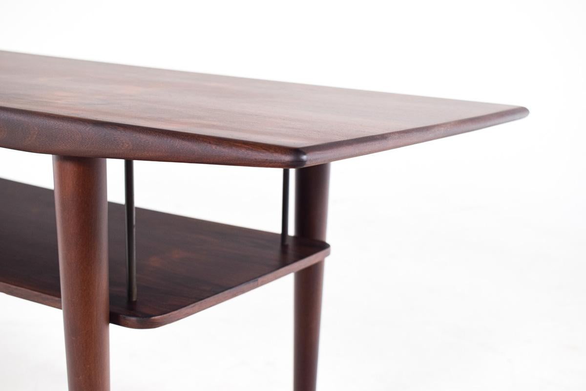 Mid-century rosewood coffee table that beautifully captures the design ethos of the era, with its clean lines, organic forms, and respect for materials. The table's most striking feature is the exquisite rosewood grain that covers its surface. The