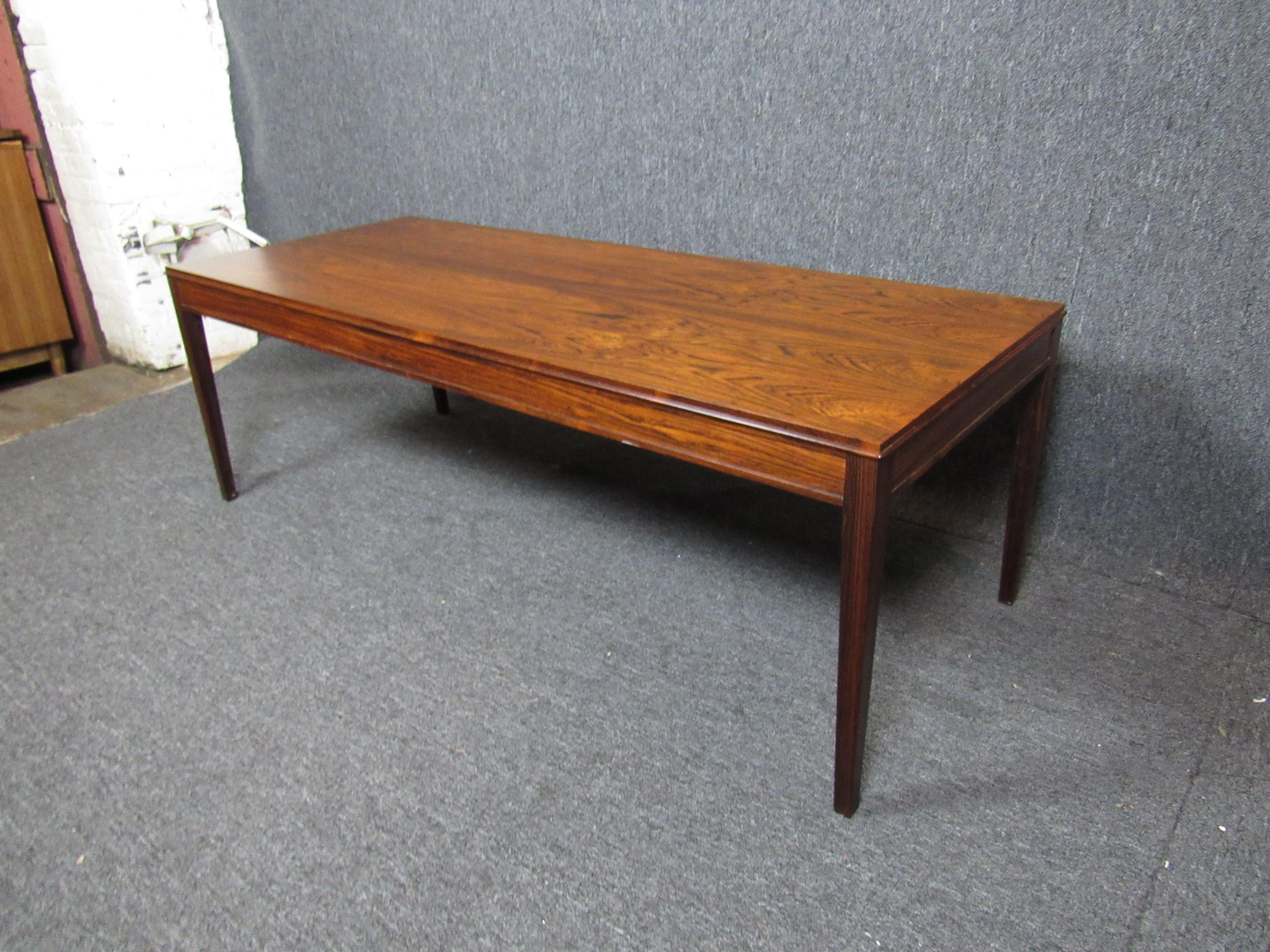 Absolutely stunning mid-century rosewood coffee table. A large tabletop, bold lines, and tapered legs show off the wood grain's natural colors and beauty. A perfect addition for any home or office. 

Please confirm location NY or NJ.
