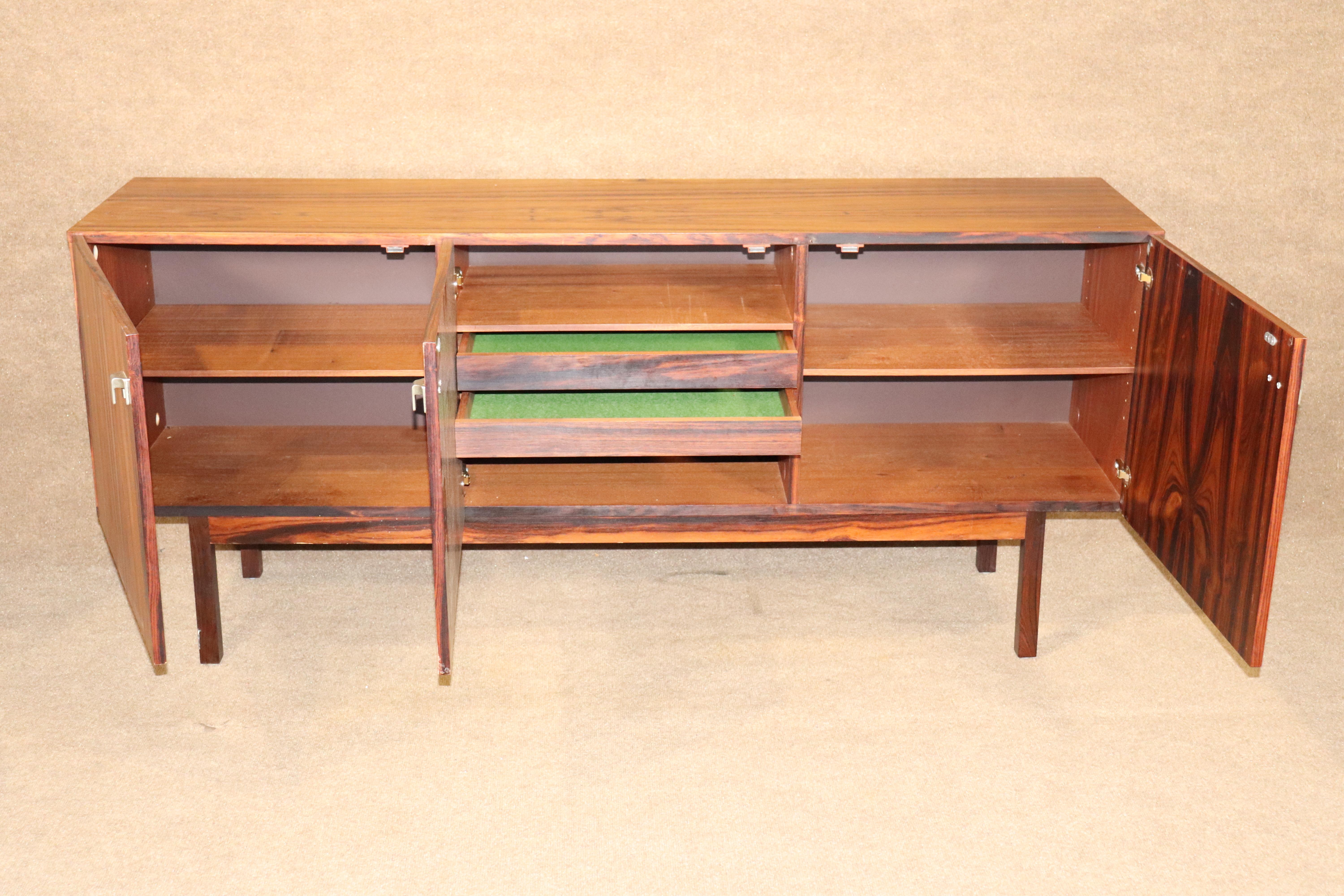Long Mid-Century Modern sideboard with cabinet storage. Rich rosewood grain throughout with accenting aluminum hardware.
Please confirm location NY or NJ.