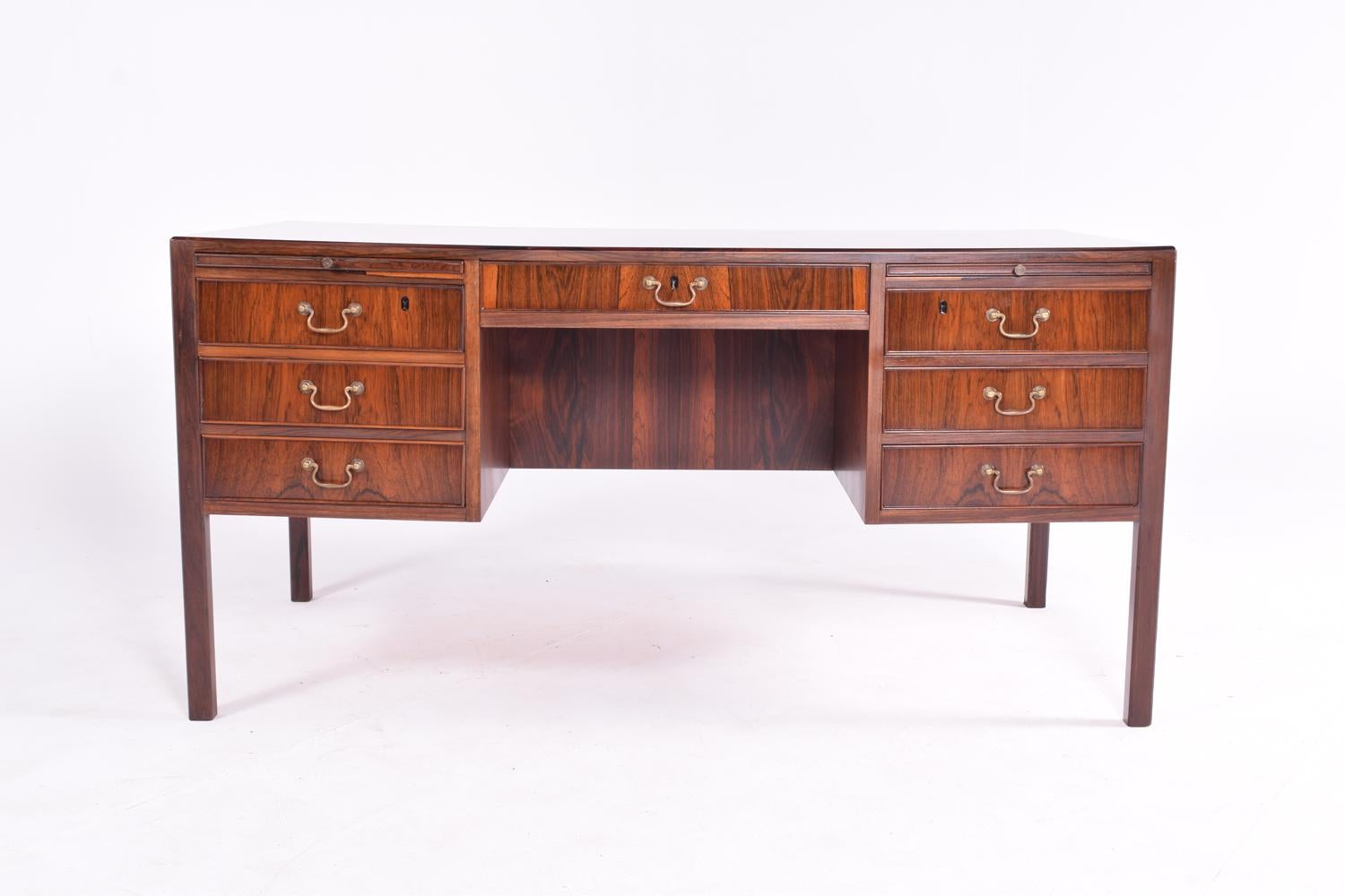 Danish desk of good proportions with elegant brass handles on drawers with extension slides, all in rosewood. The other side with book shelf. Straight square legs.