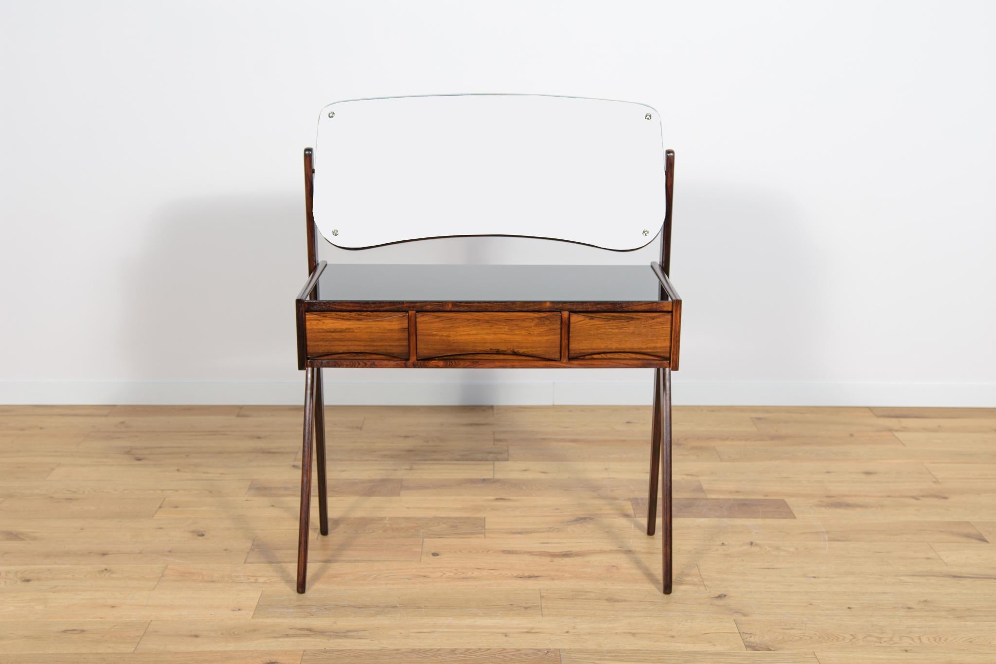 A small rosewood dressing table designed by Arne Vodder for Ølholm Møbelfabrik. The dressing table has three drawers. There is an adjustable mirror in the frame above the dressing table. The furniture has been completely renovated, it has been