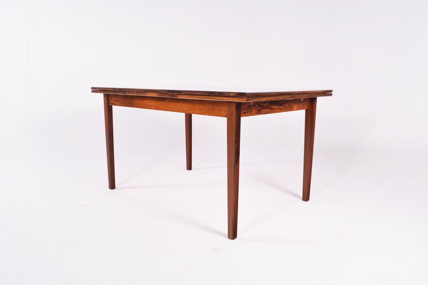 Beautiful Scandinavian Modern dining extendable table. Vivid rosewood veneer dining table includes two interior leaves which pull out at either end of the table to seat eight/ten people. Measures; Extension with 45 cm each. Extended: 228 cm.