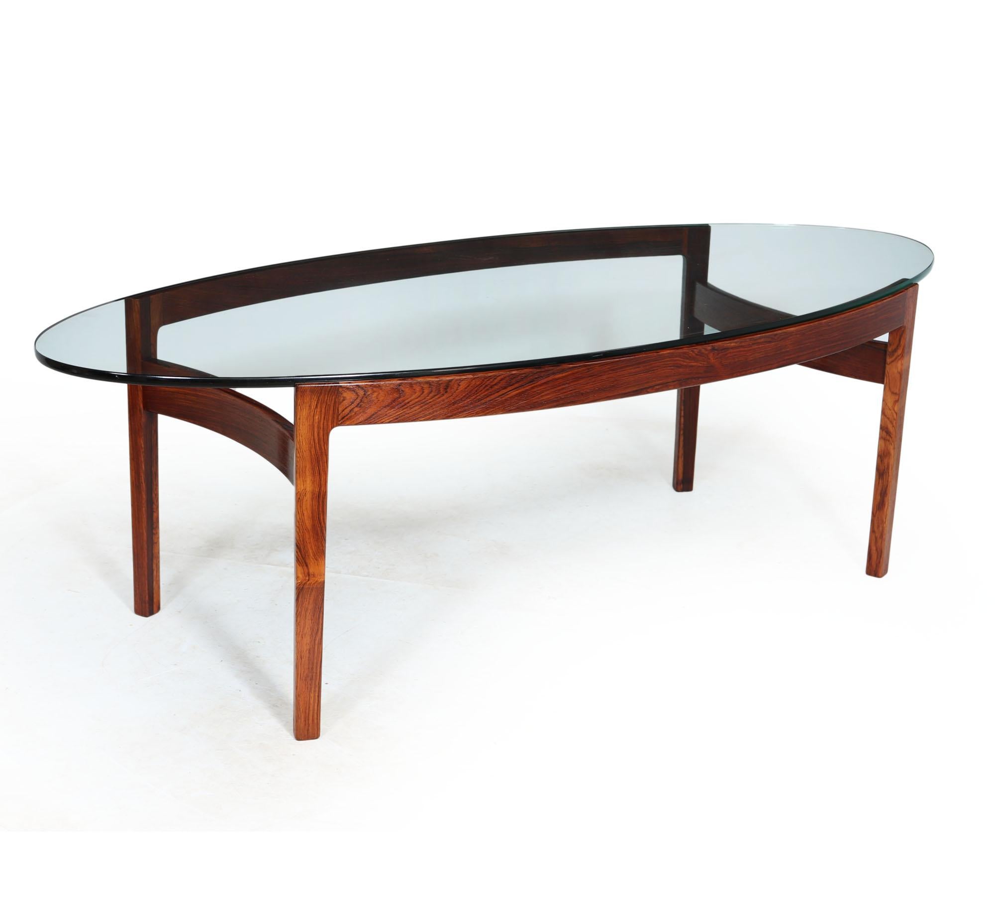 A truly stunning designed coffee table very much similar to the work of Sven Ellekaer, having solid rosewood frame and oval glass top, the base has number stamped to the underside, the glass in in excellent condition with minimal wear and the frame