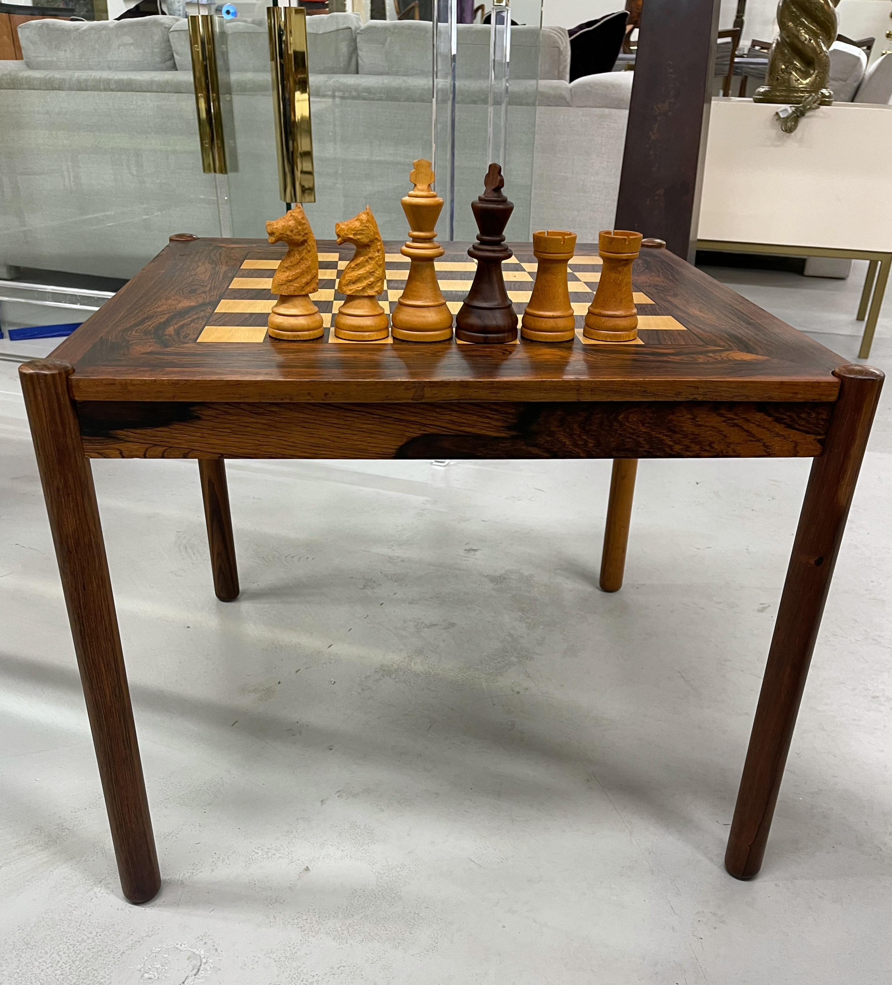 A stunning rosewood table by Georg Petersen of Denmark. The top flip to be used as a game table or as a table. Beautiful graining and color. We are including a large complete chess set. There are some marks stains and imperfections to both sides of