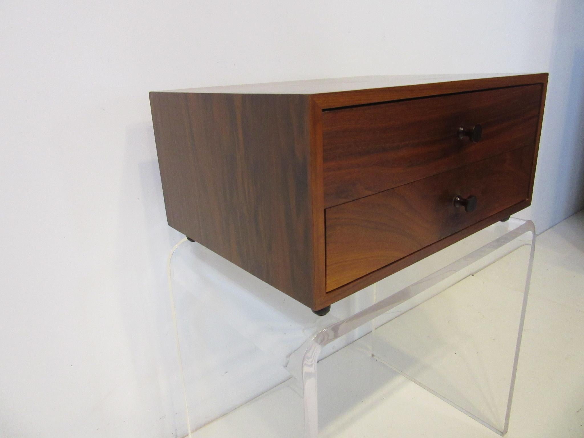 A two drawer rosewood Jewelry or watch box with darker turned rosewood pulls sits on black satin cast legs. This very well crafted piece has dovetail construction inside using birch wood and can be used on top of a dresser or in your dressing area,