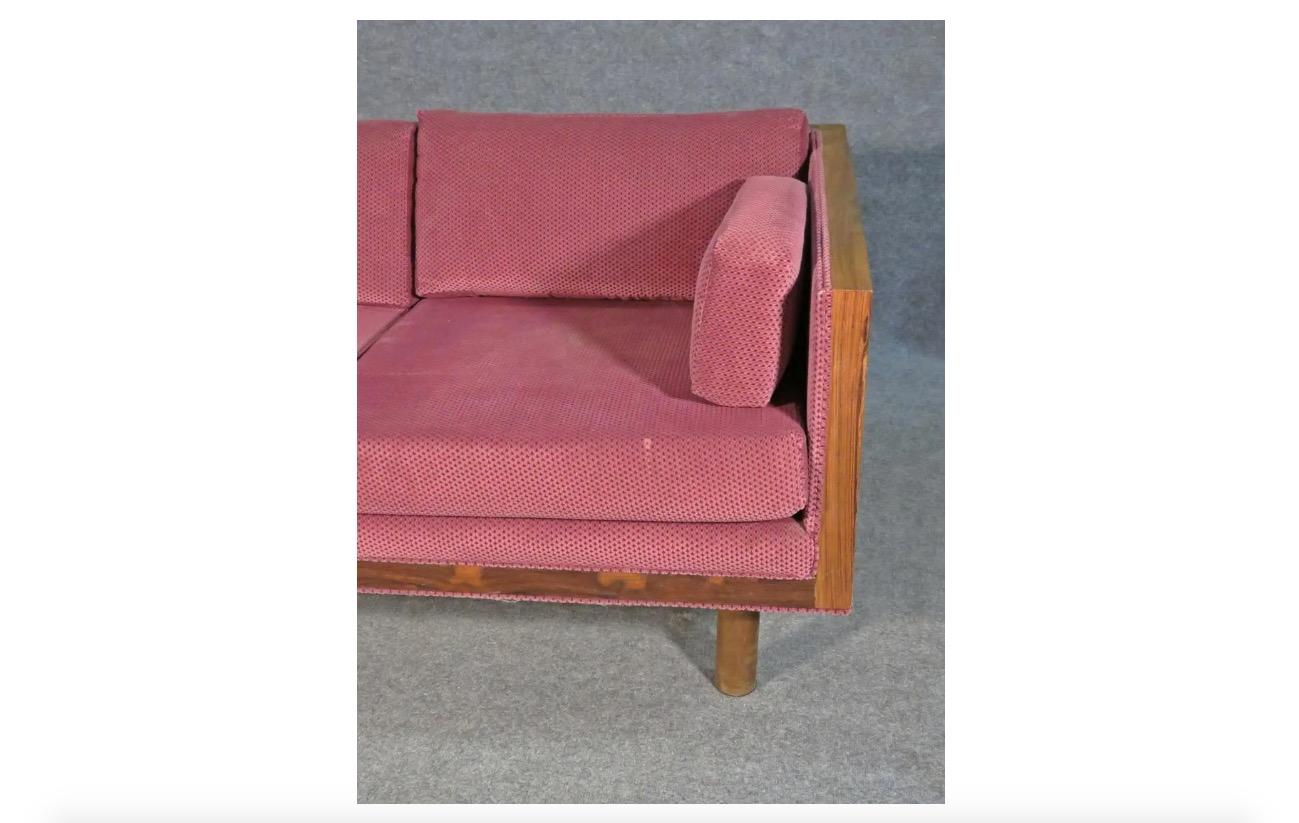 Combining a rosewood frame with unique raspberry-red upholstery, this vintage loveseat is a great way to add stylish and timeless Mid-Century Modern design to any room. Please confirm item location with seller (NY/NJ).