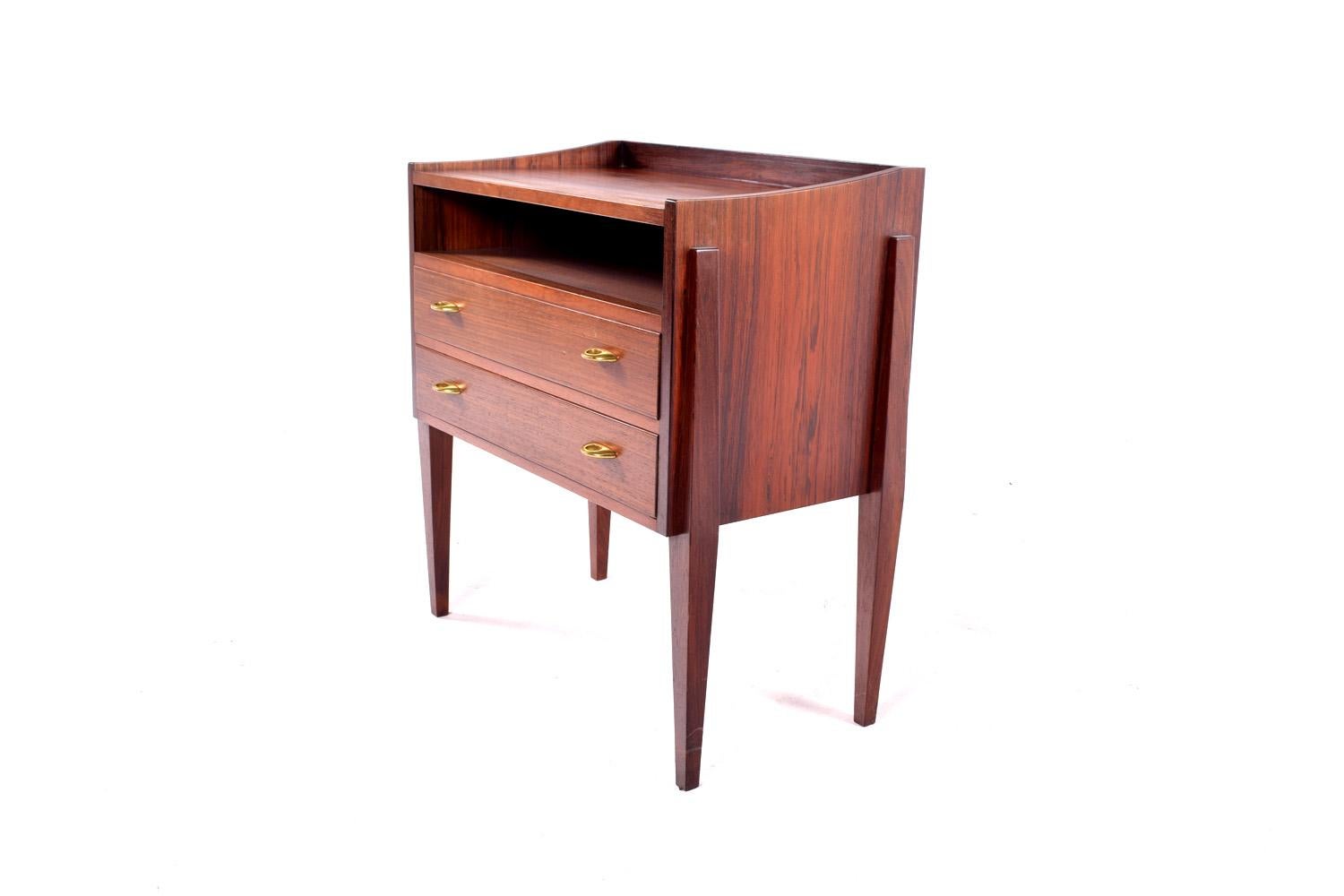A wonderful rosewood chest of drawers, nightstand or end table by Frode Holm for high end Danish furniture company Illums Bolighus of Denmark. The table features brass pulls and tappered legs with two drawers.