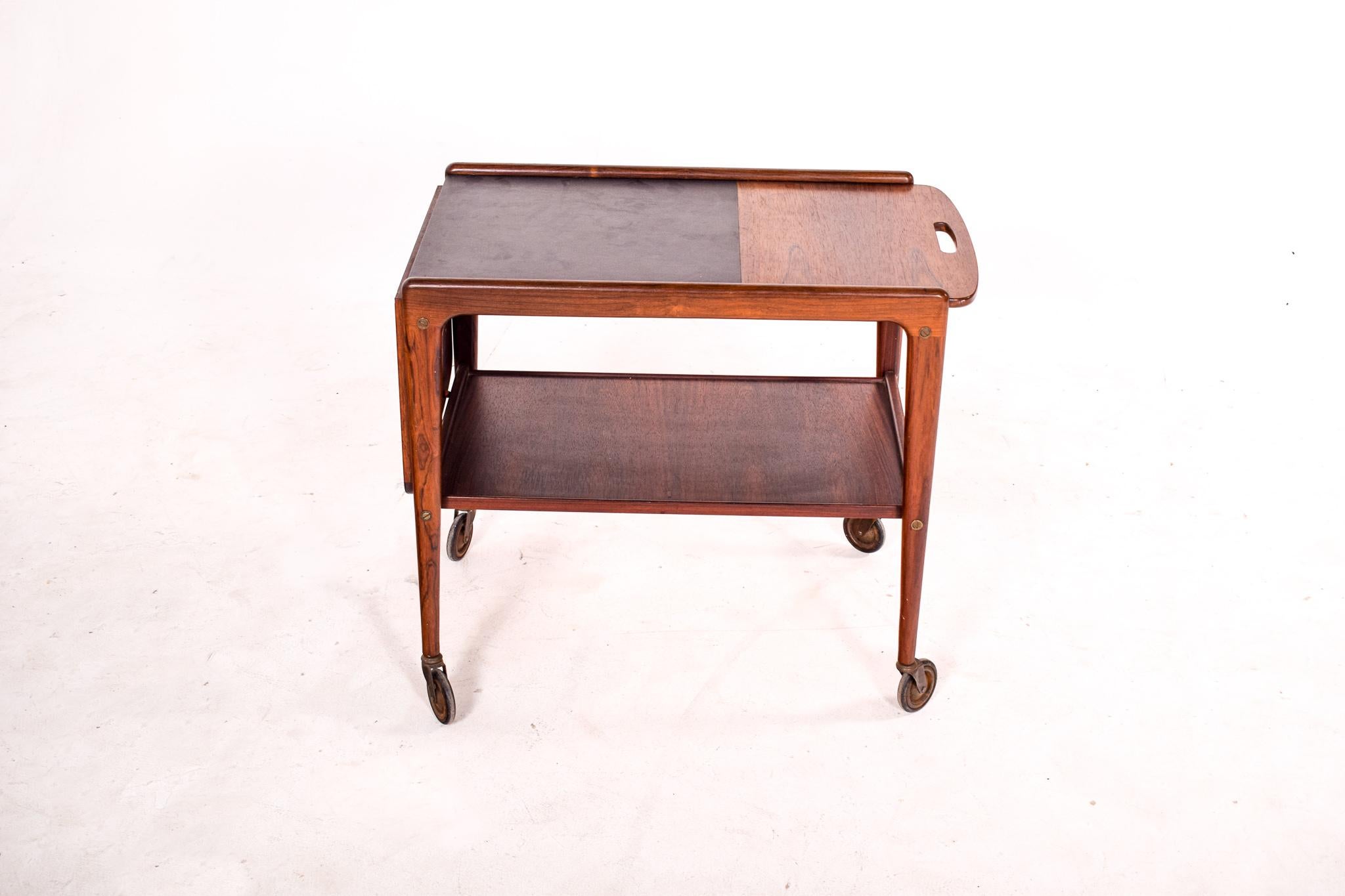 Mid Century rolling tea cart or serving bar cart in rosewood, designed by Yngve Ekstrom and made in Sweden by Kallemo. This tea cart has a unique design feature, the top slides to one side and expands. We believe this model was produced Circa 1950.