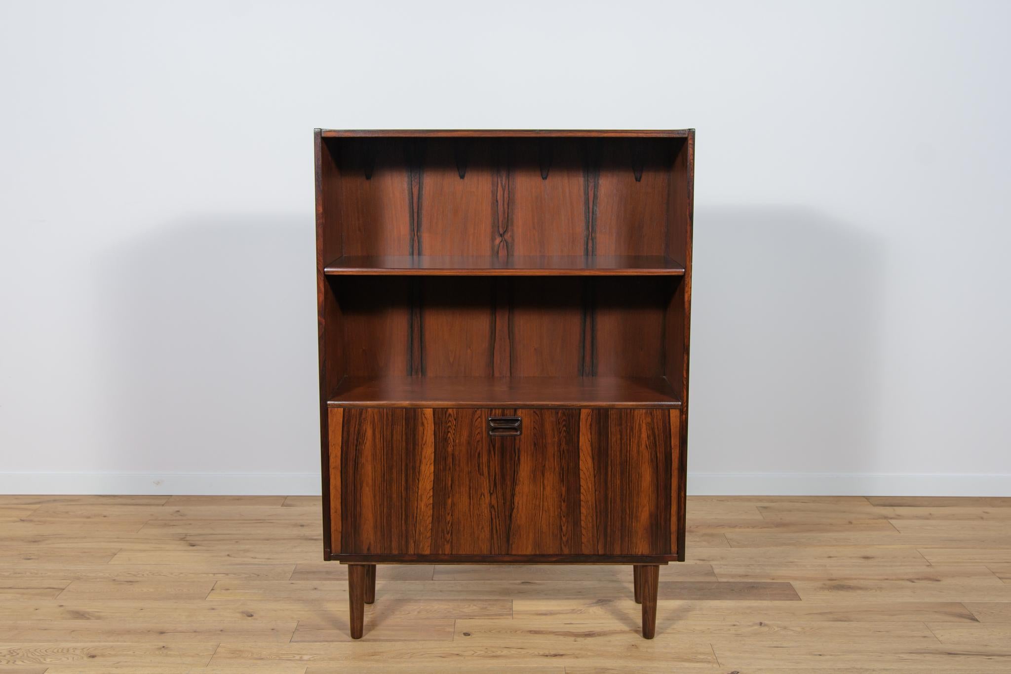 This bookcase made of teak wood in Denmark in the 70s. There are open shelves in the upper part of the rack, in the down part is a cabinet with a profiled handle. The bookcase after a comprehensive renovation, cleaned of the old surface, finished